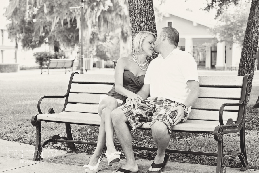 engagement session couple cuddling on bench in black and white