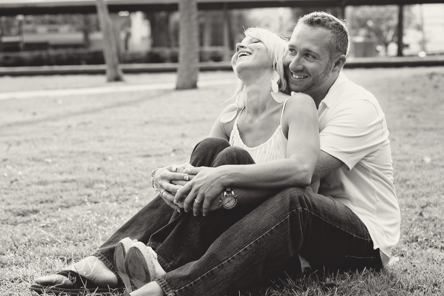 engagement couple laughing sitting in grass