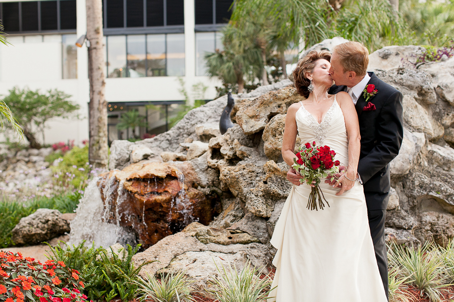bride and groom kissing by water fountain
