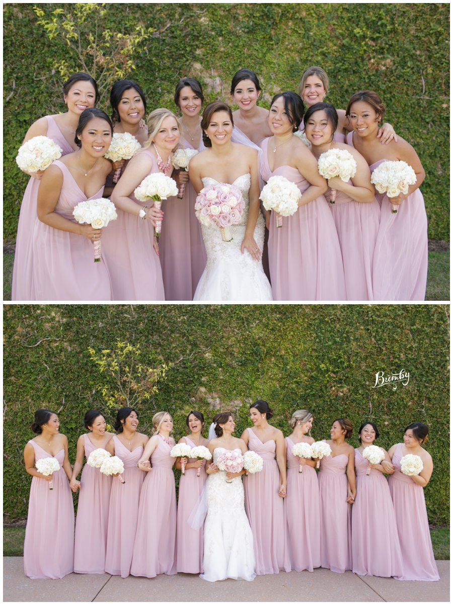 Bride and bridesmaids posing in front of a wall covered with greenery.