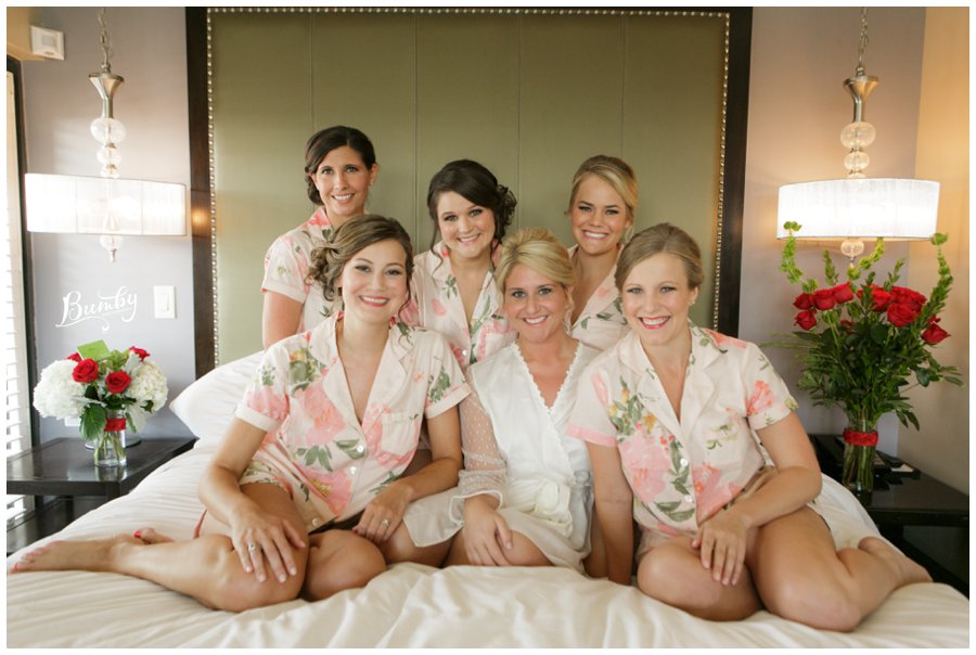 Bride and her bridesmaids sitting on the bed.