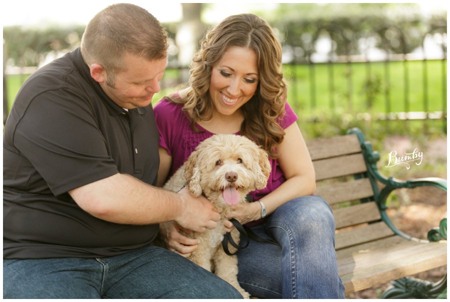 Couple sitting on the bench while holding their dog.