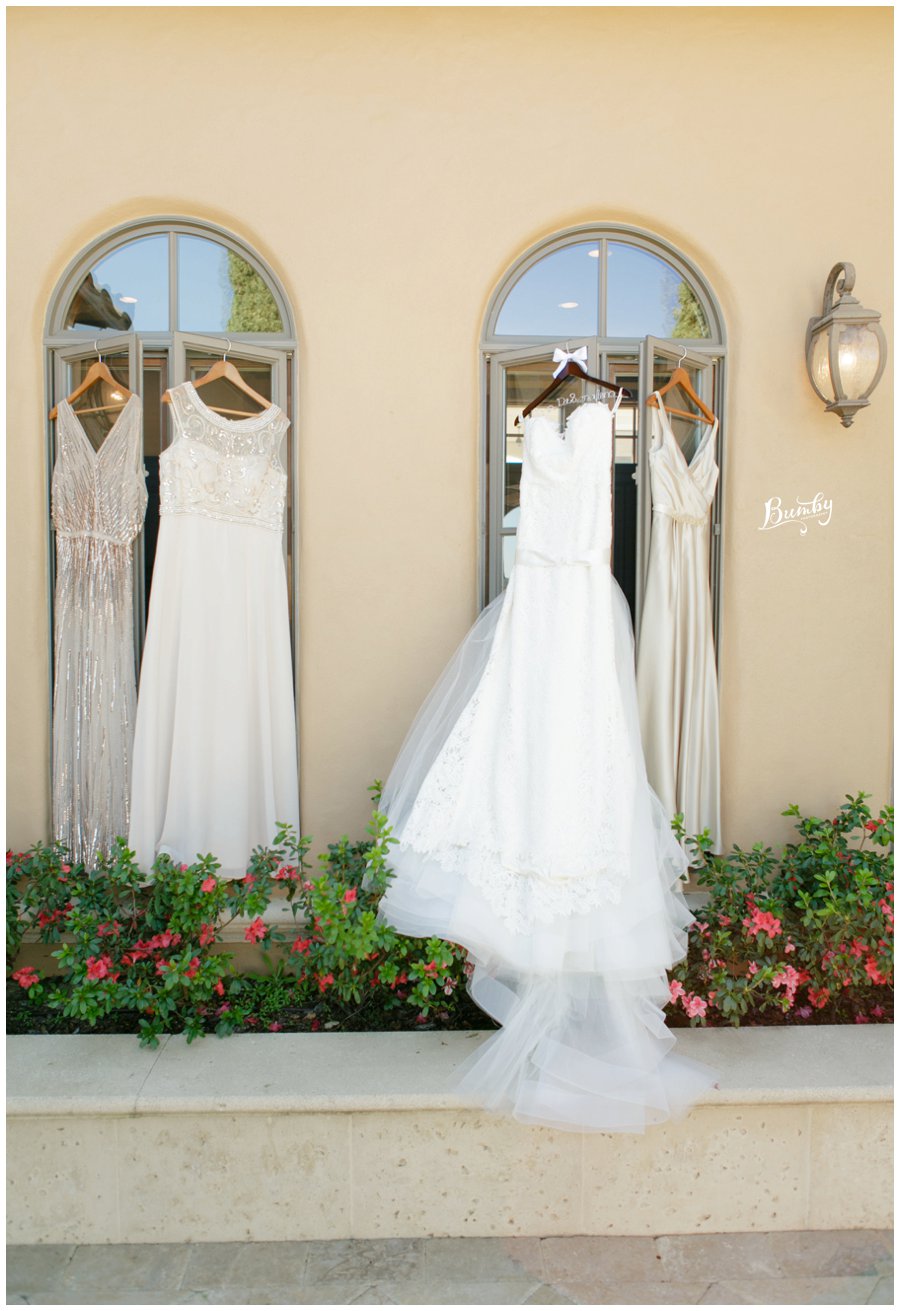 Brides wedding dress and bridesmaids dress hanging on windows.