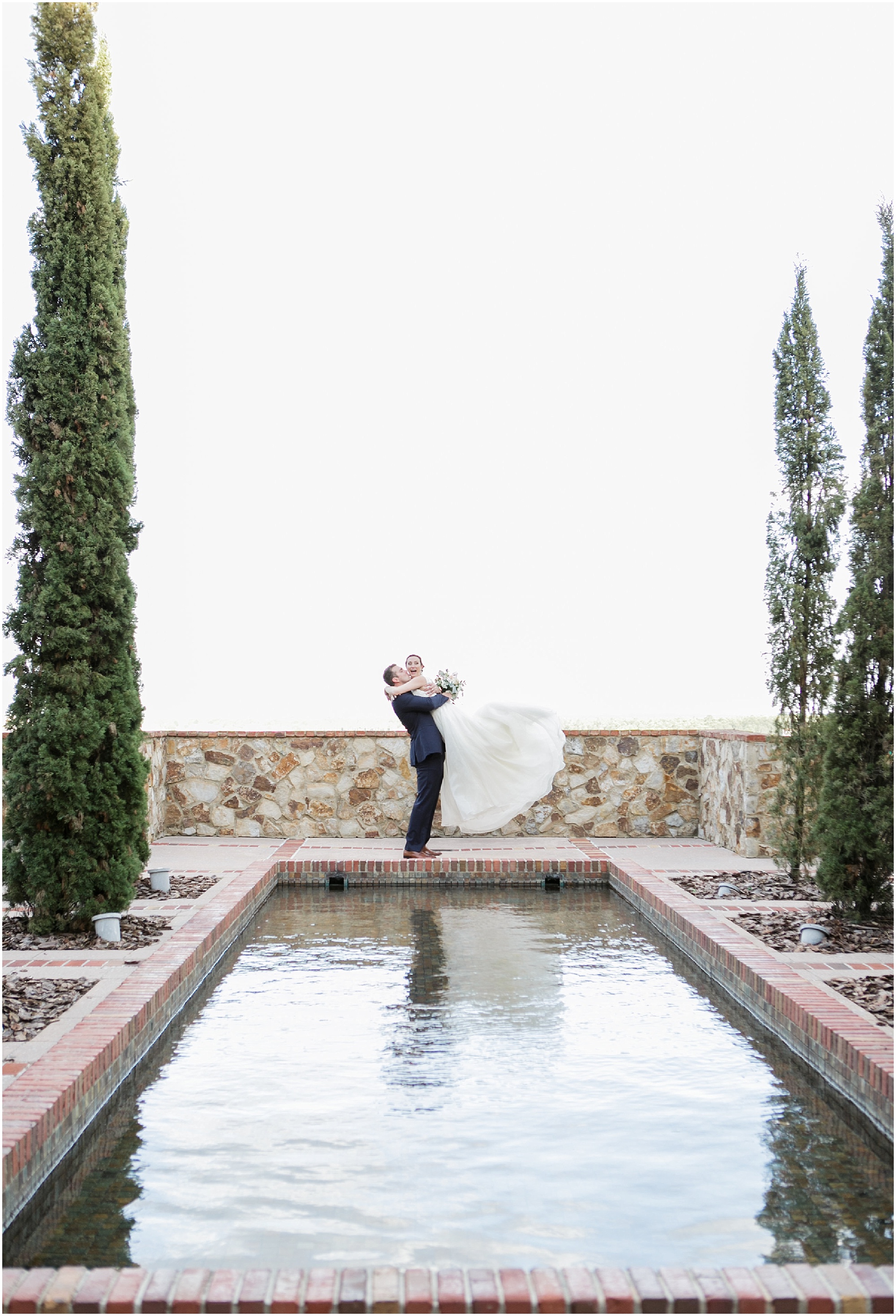 Groom lifting laughing bride at Bella Collina pond