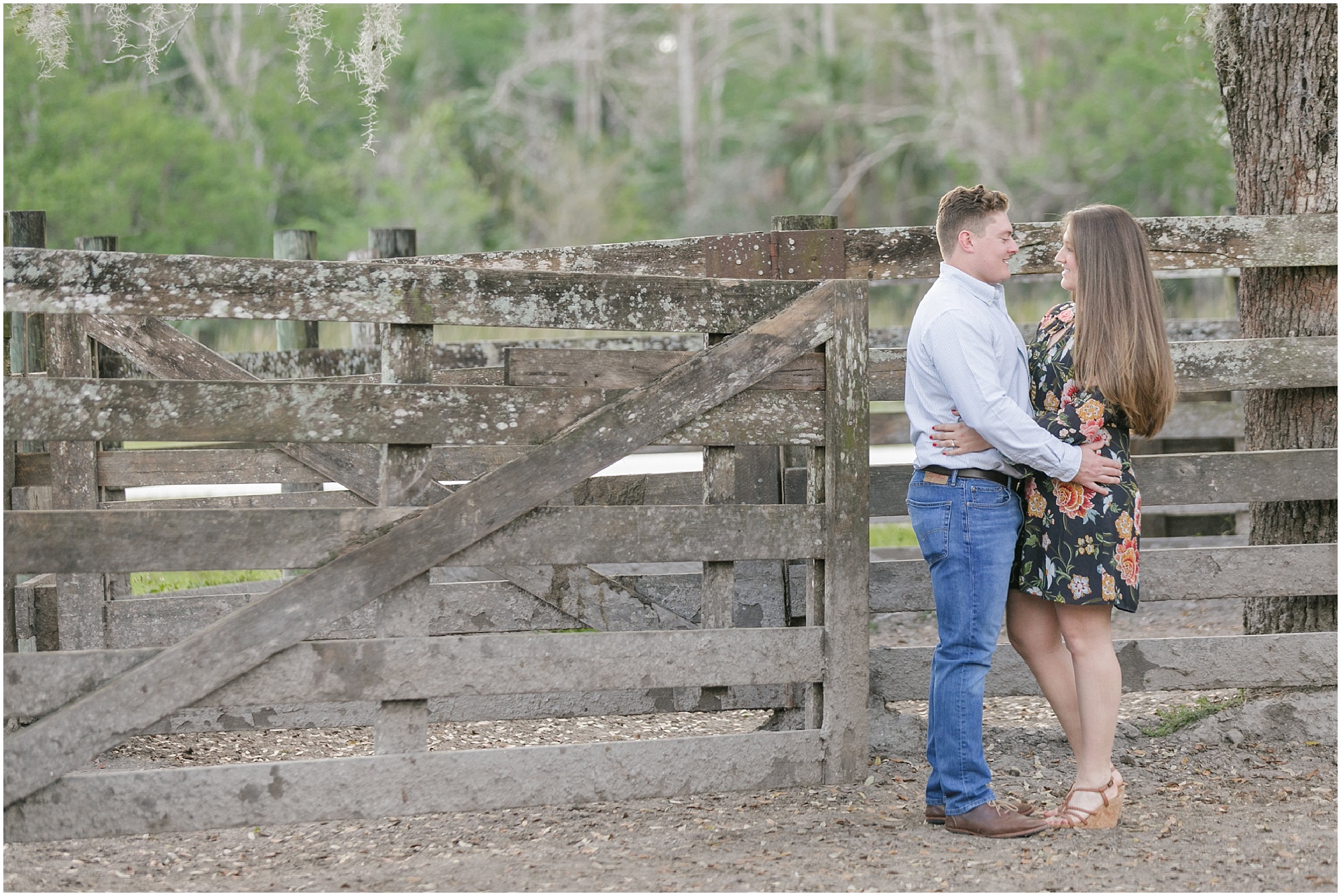 rustic outdoor couple holding each other next to wooden fence