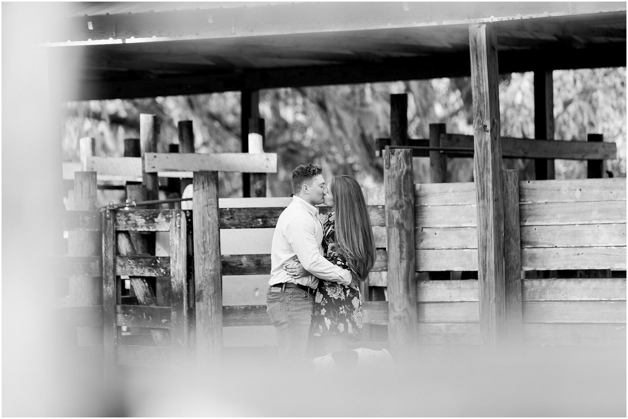 couple kissing near stalls at rustic outdoor engagement session