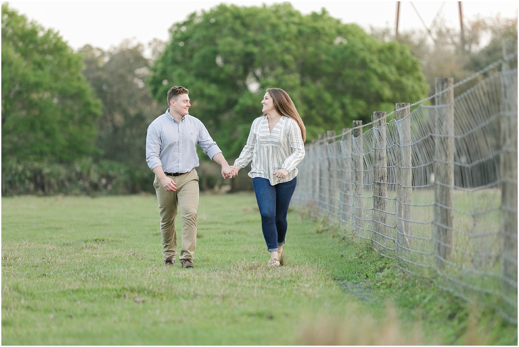 engagement session couple holding hands and walking next to wire fence