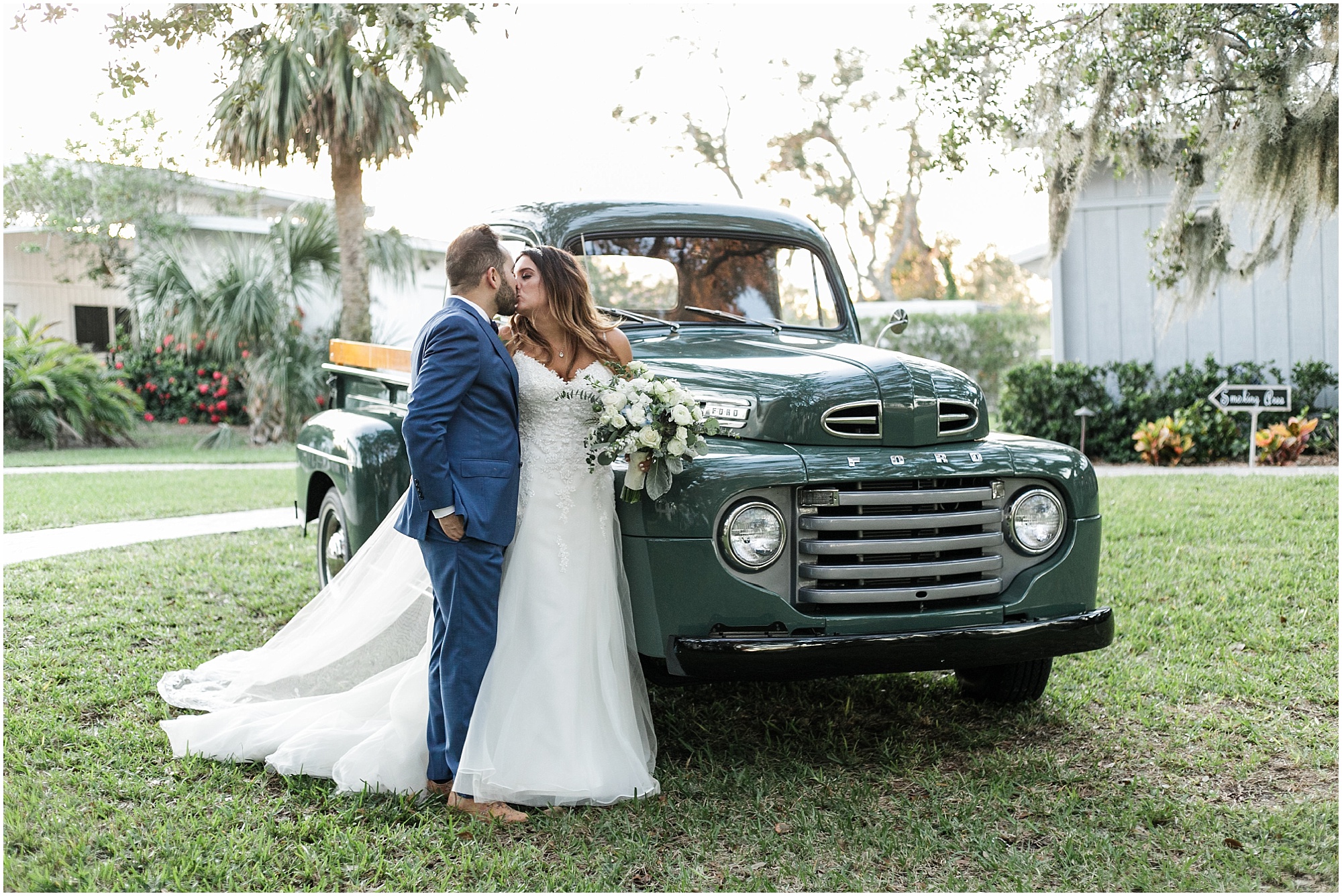 Bride and groom kissing next to antique Ford truck