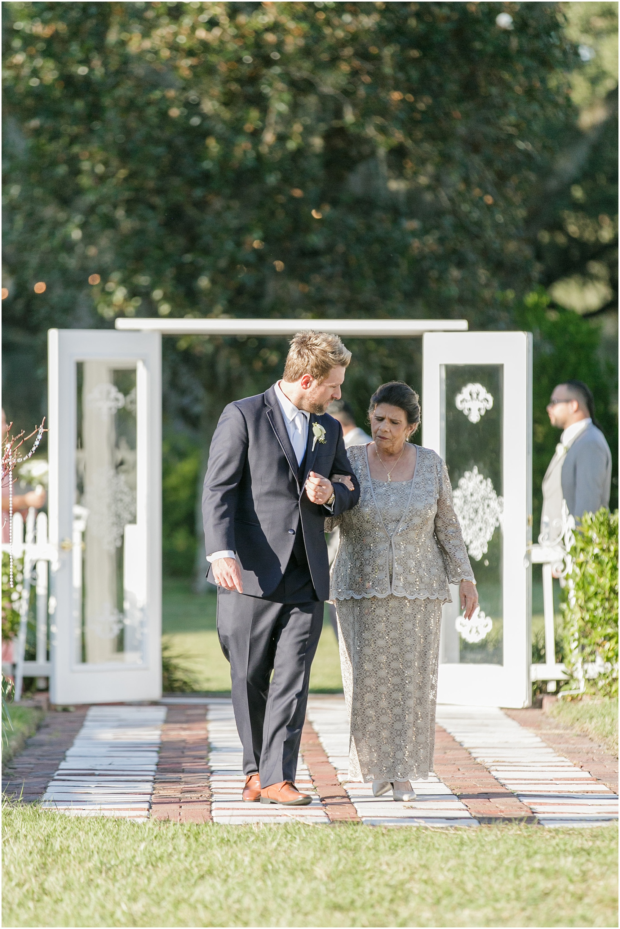 Groom walking with mom down the aisle. 