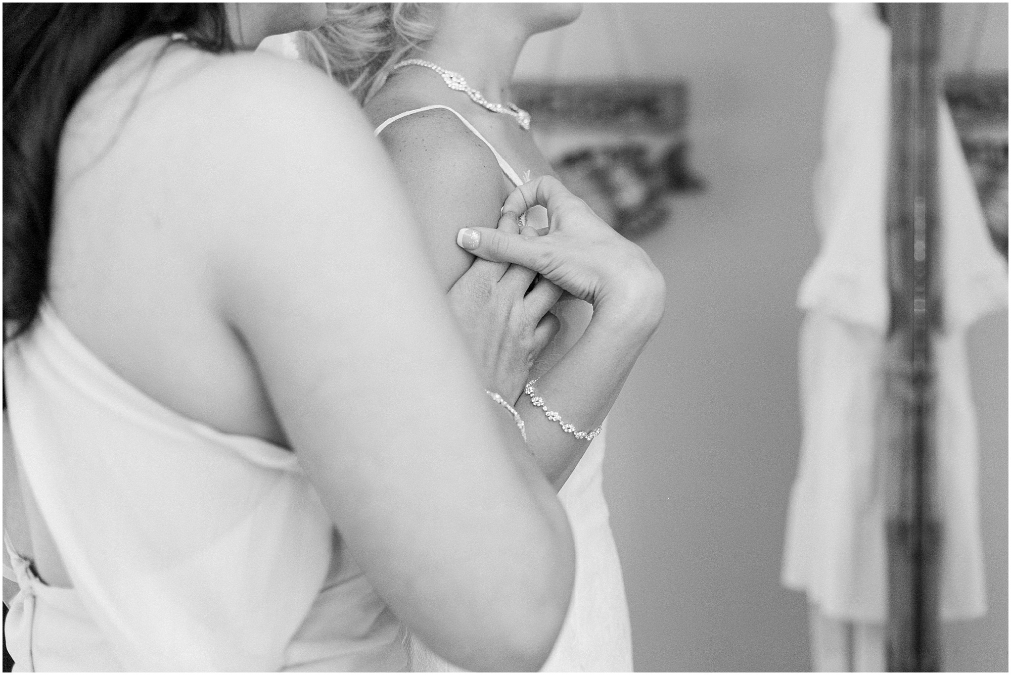 Black and white photo of bride holding her bridesmaids hand.