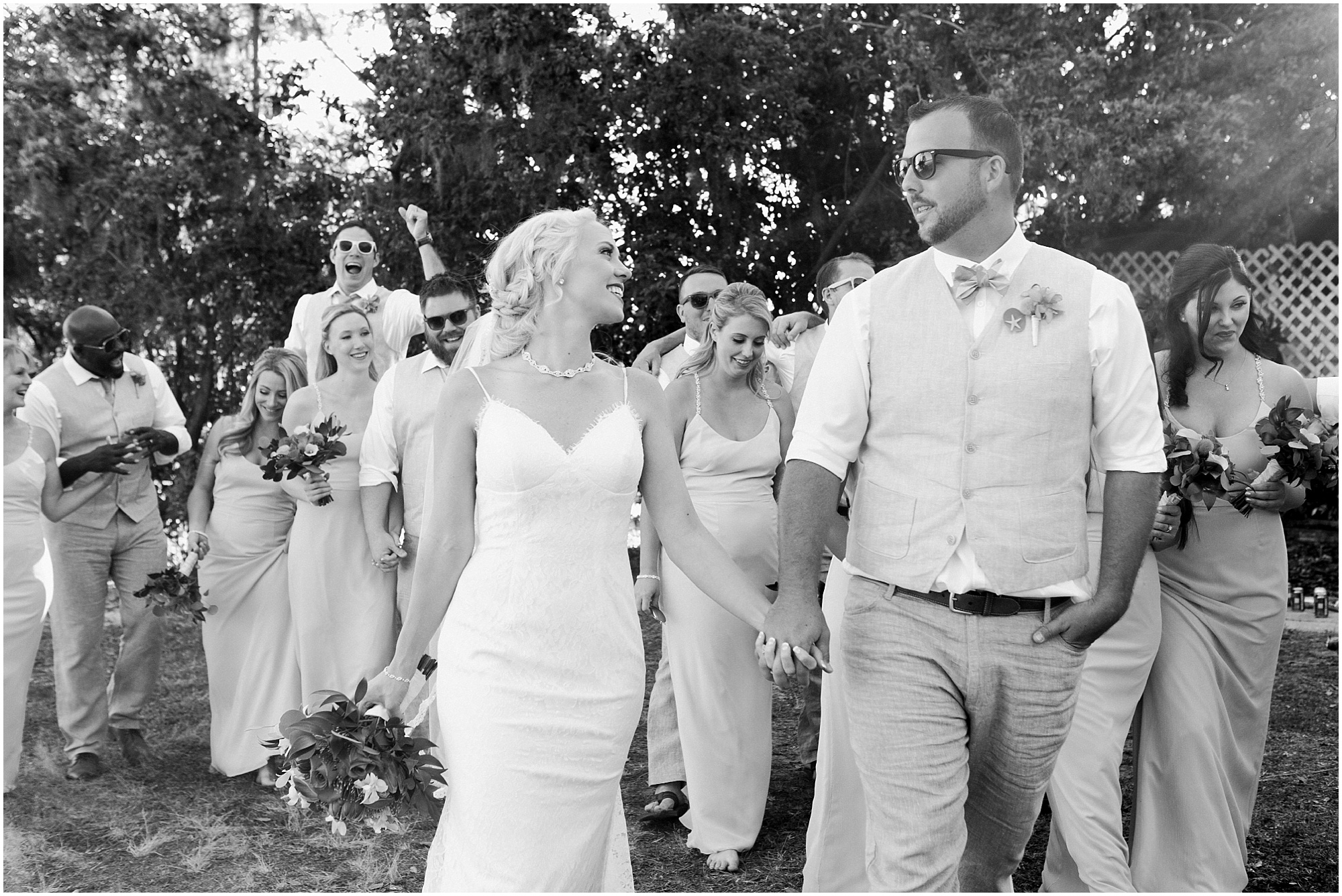 Black and white photo of bride and groom walking with their wedding party.