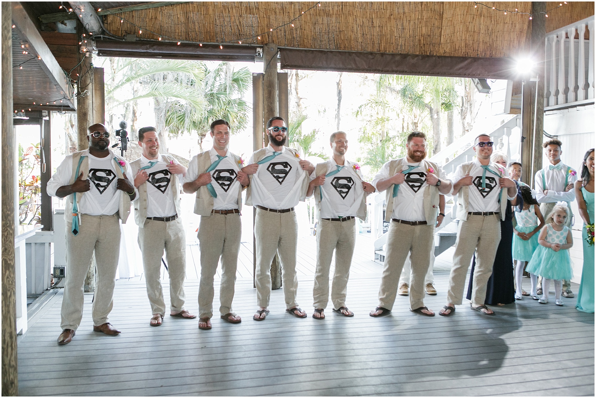 Groomsmen revealing Superman shirts under their wedding attire.