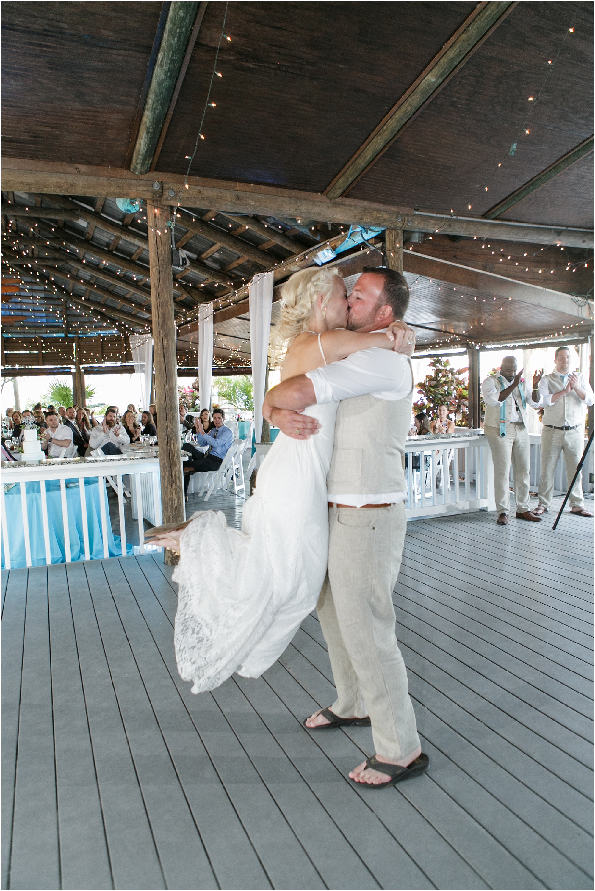 Groom lifts bride up as they share a kiss. 