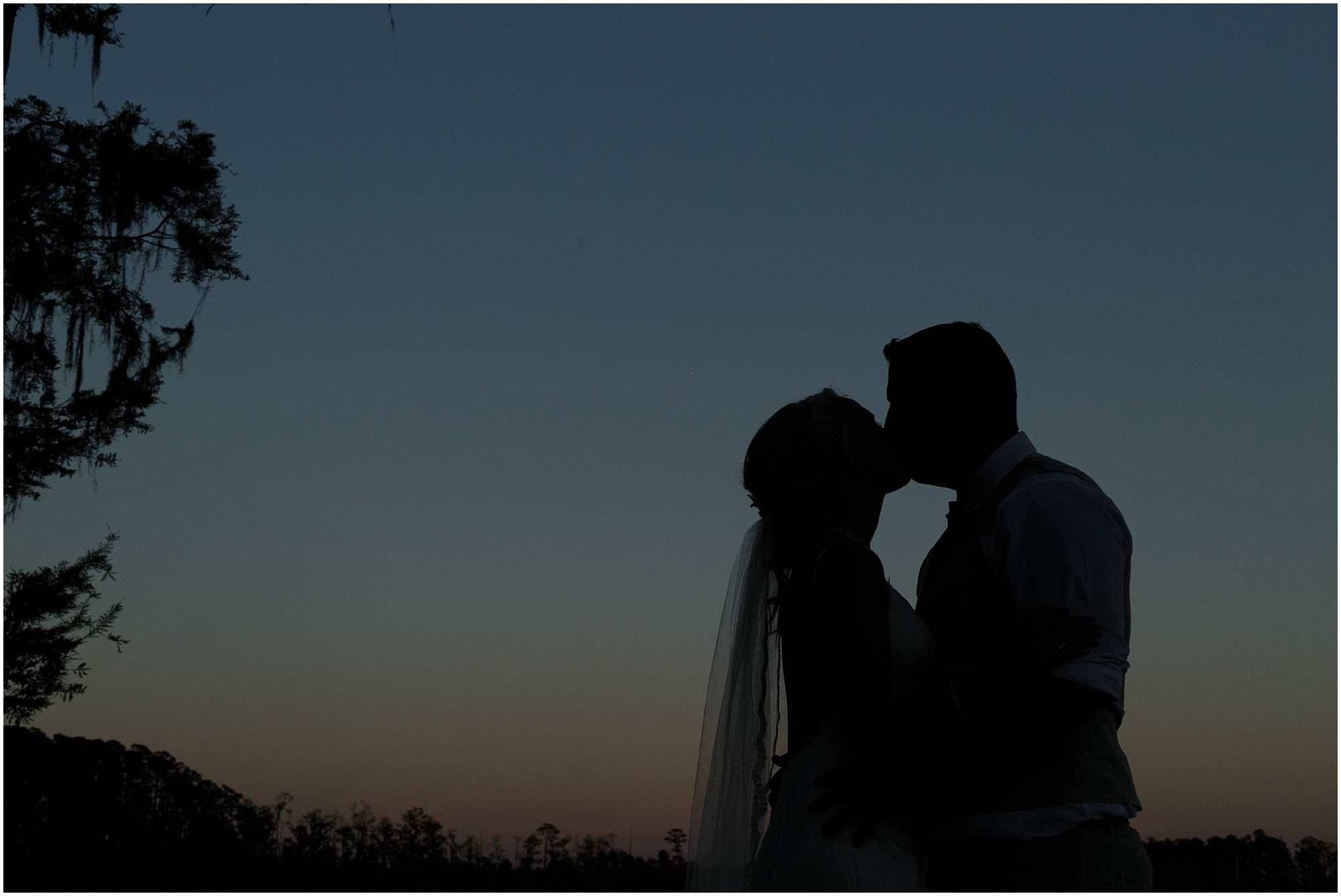Silhouette of newlyweds kissing at sunset.
