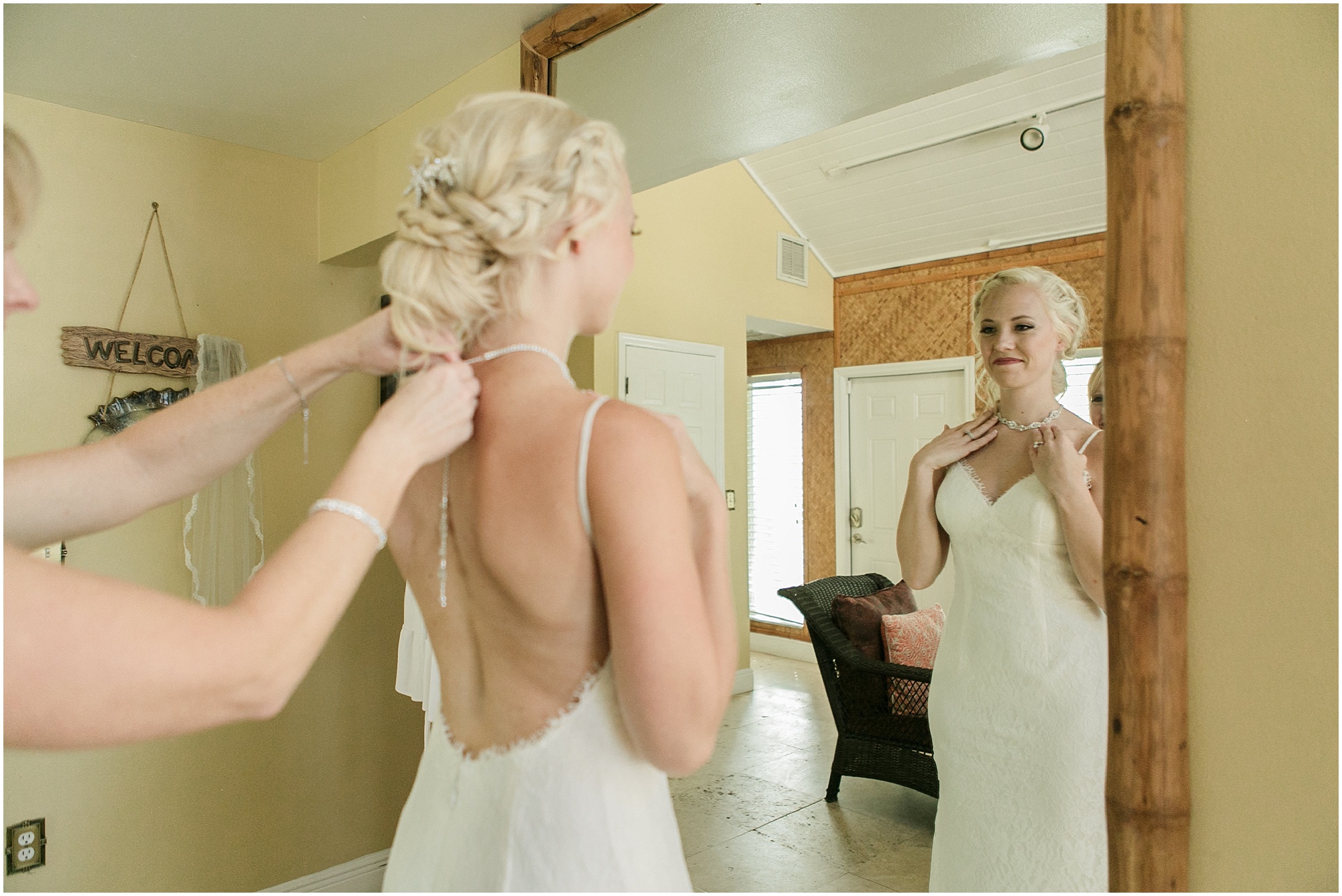 Mother helping bride put her necklace on.