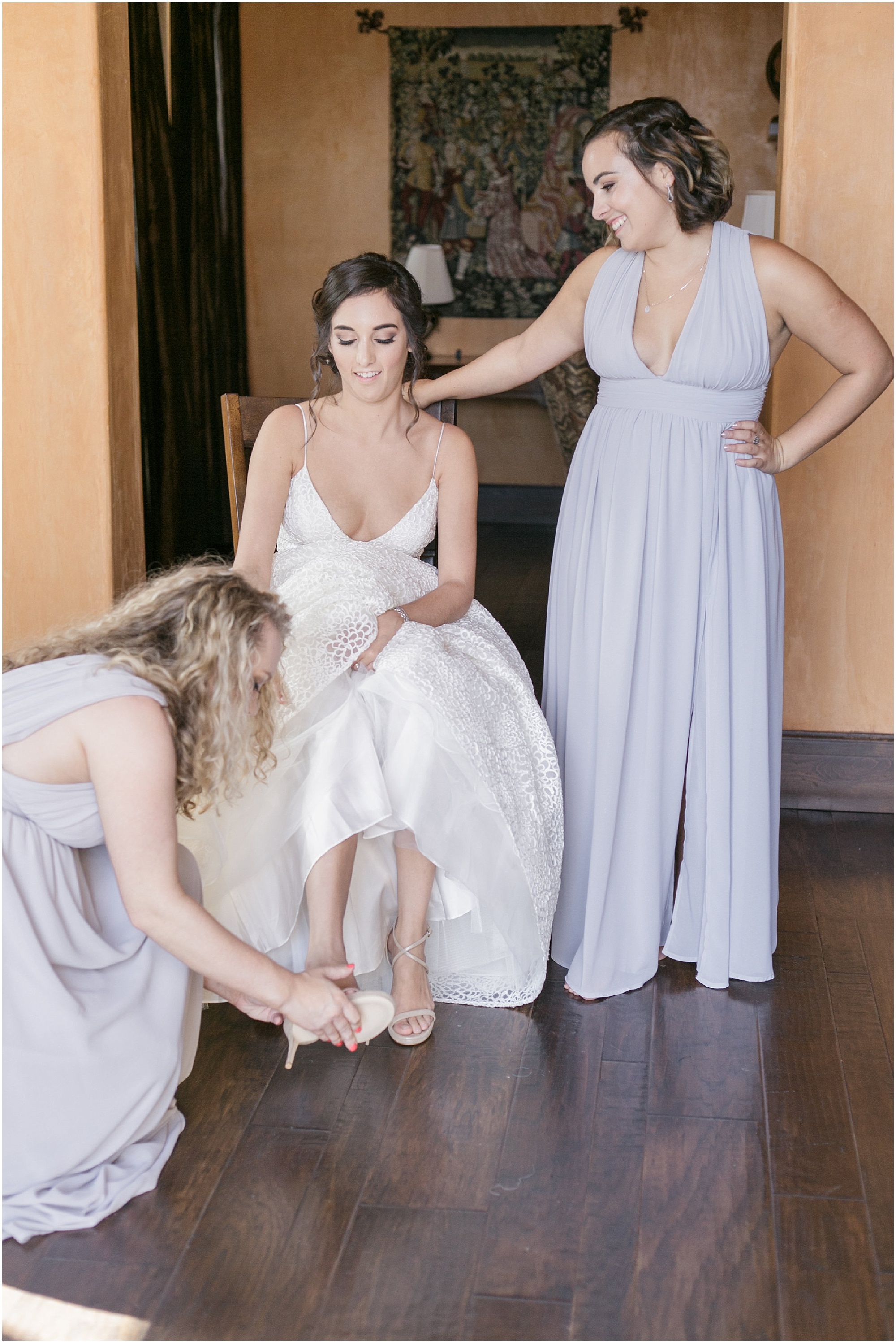 Bride putting on her shoes with the help of her bridesmaids. 