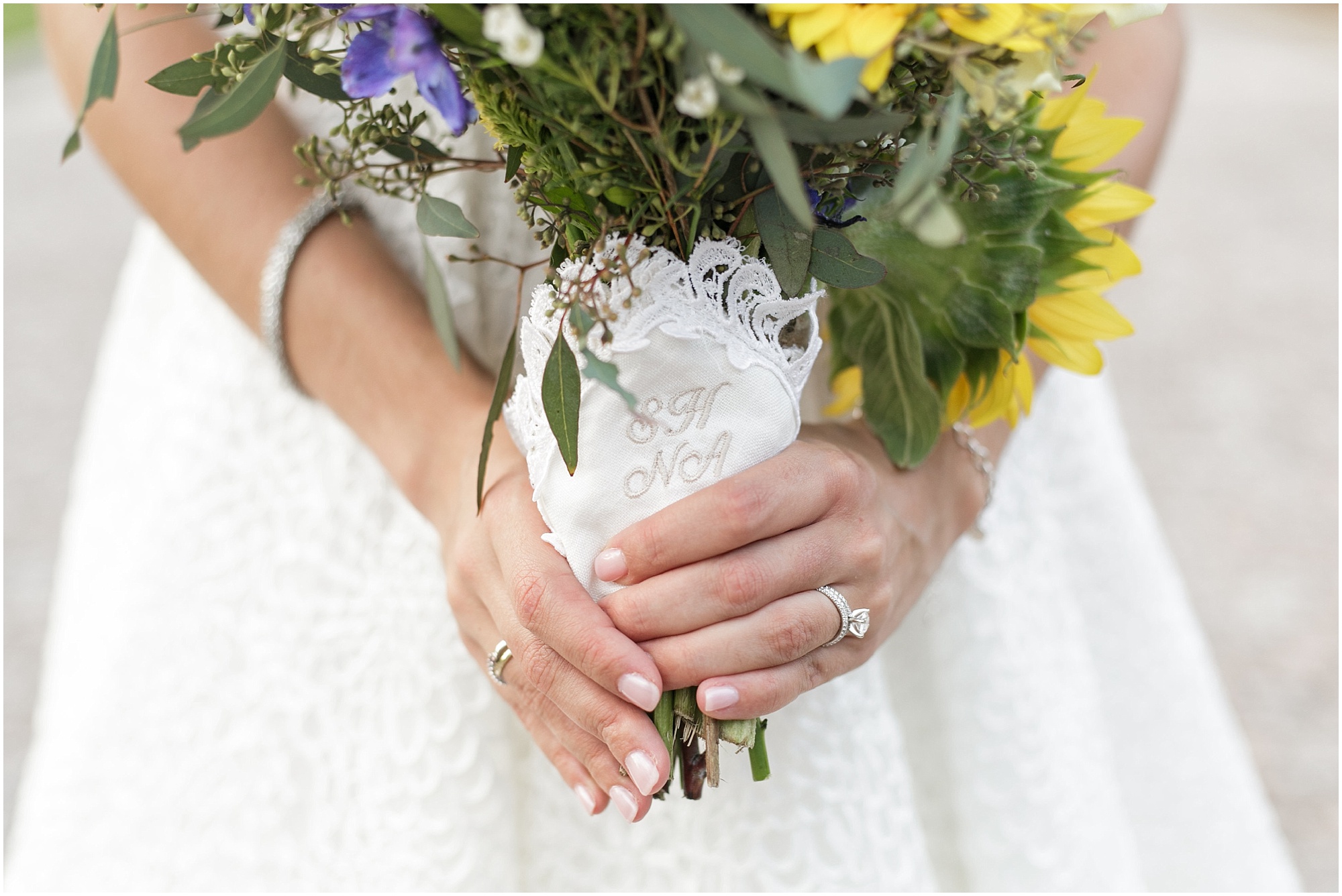 Bride holding her bouquet with a white handkerchief around the stems. 