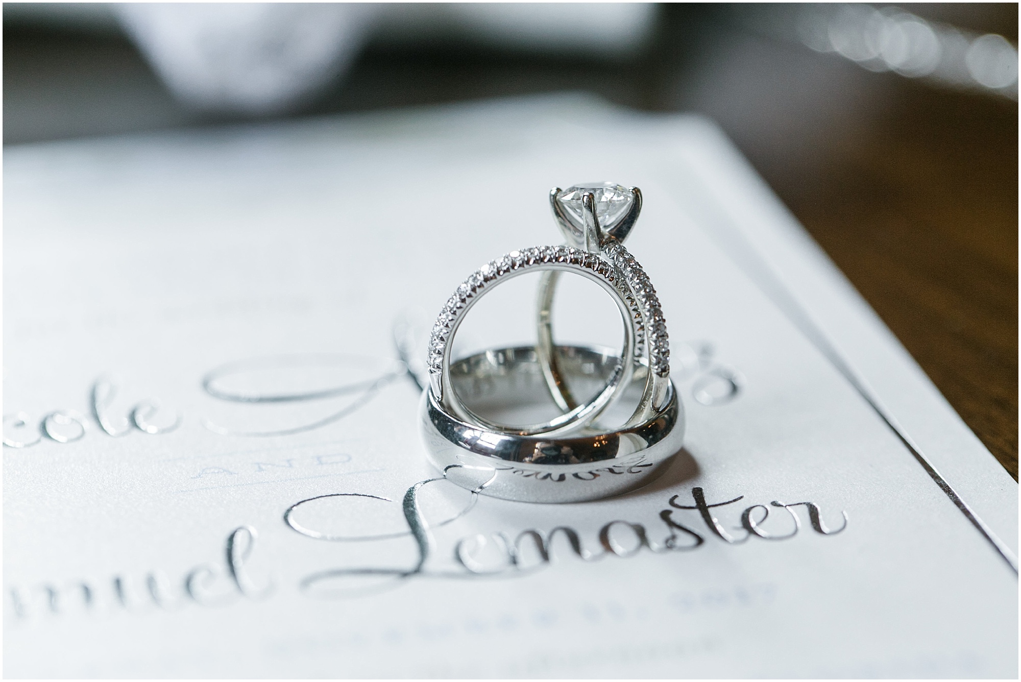 Wedding rings sitting on top of a wedding invitation.