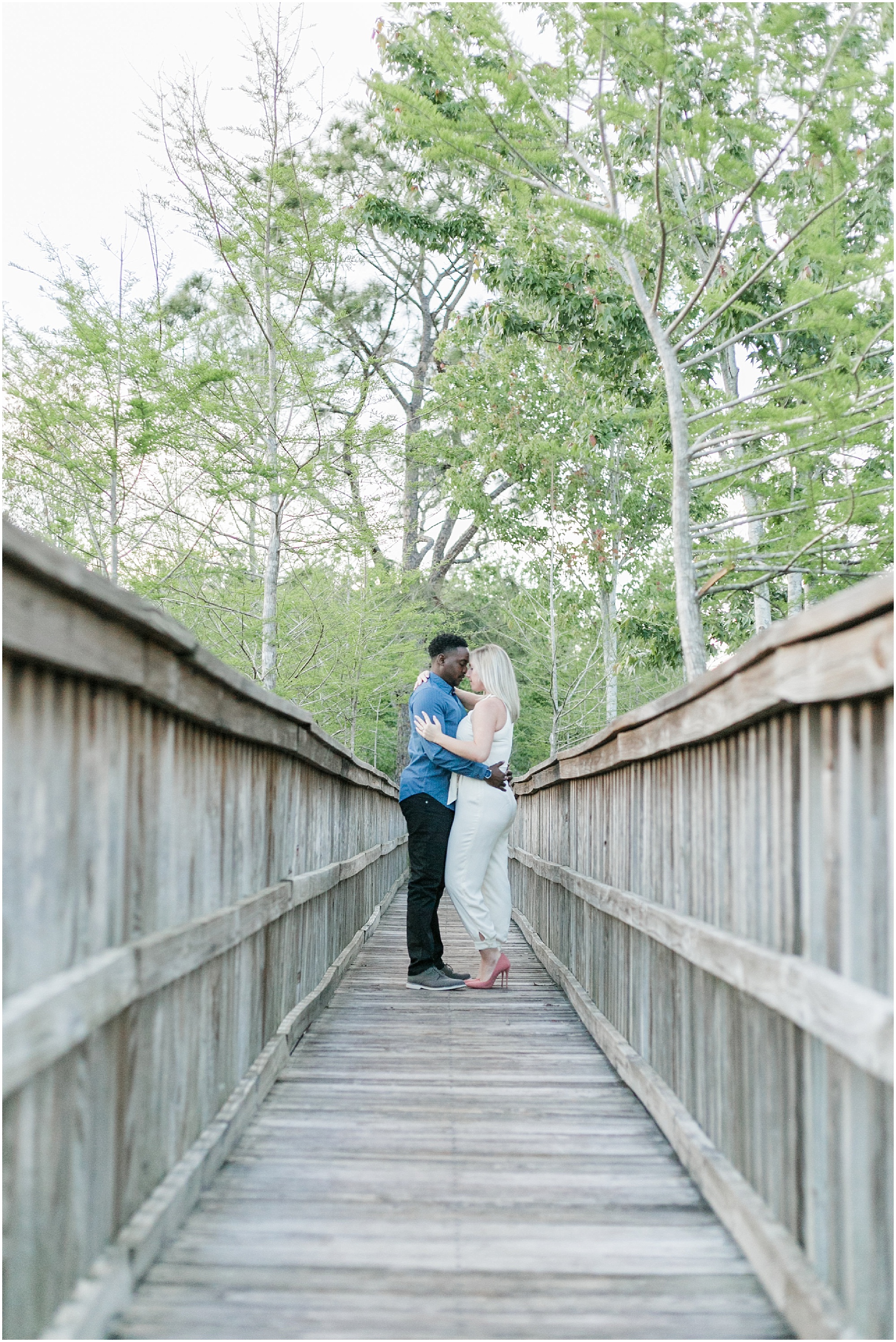 Couple standing on a wooden dock and hugging.