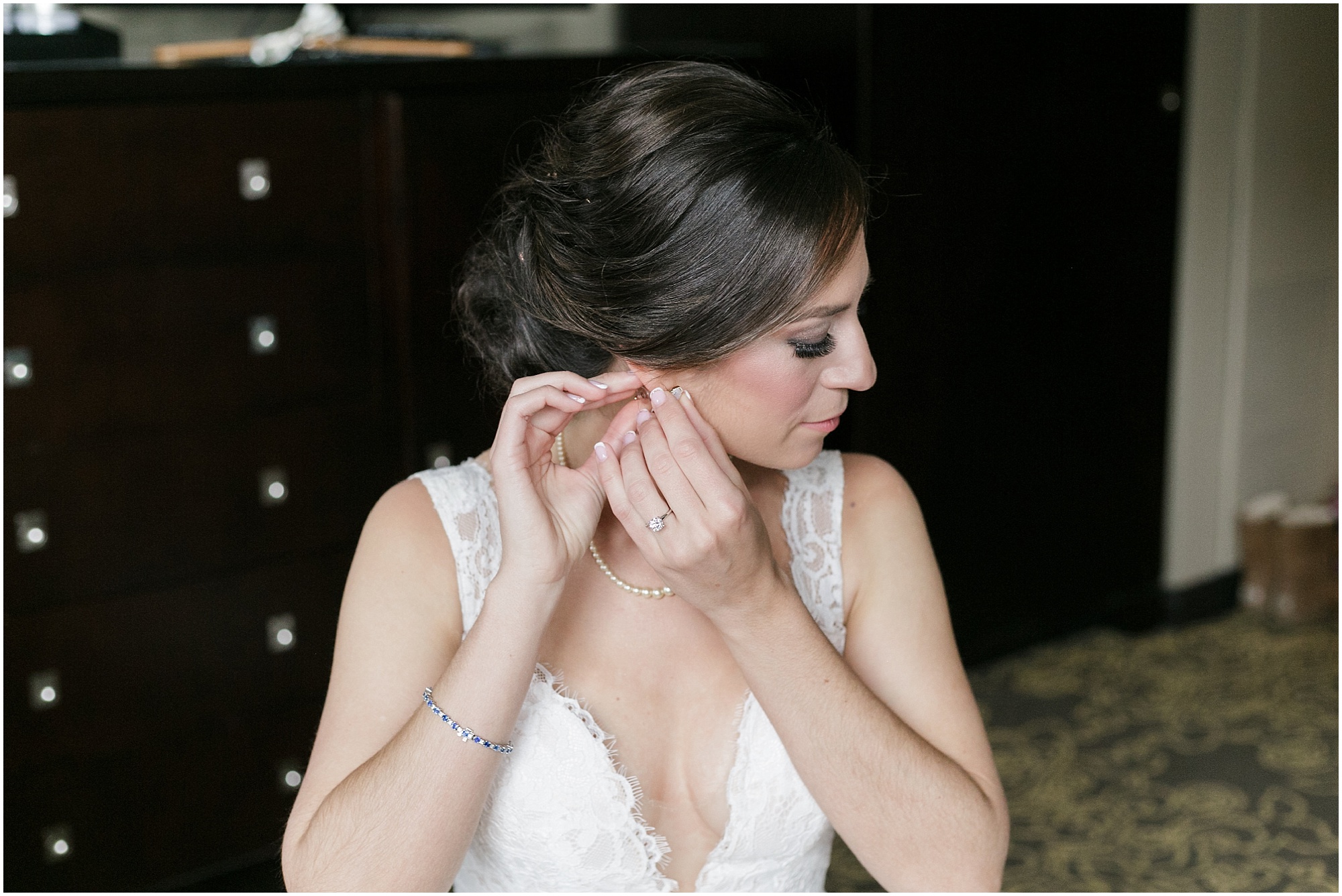 Bride putting her right earring on while getting ready for her wedding in downtown Orlando.