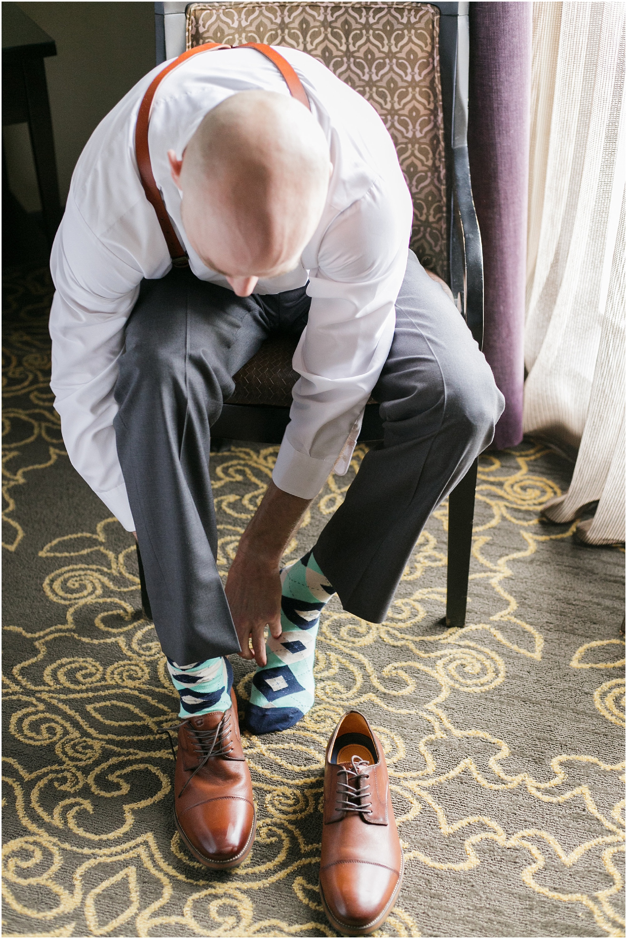 Groom putting on his shoes as he gets ready for his wedding.