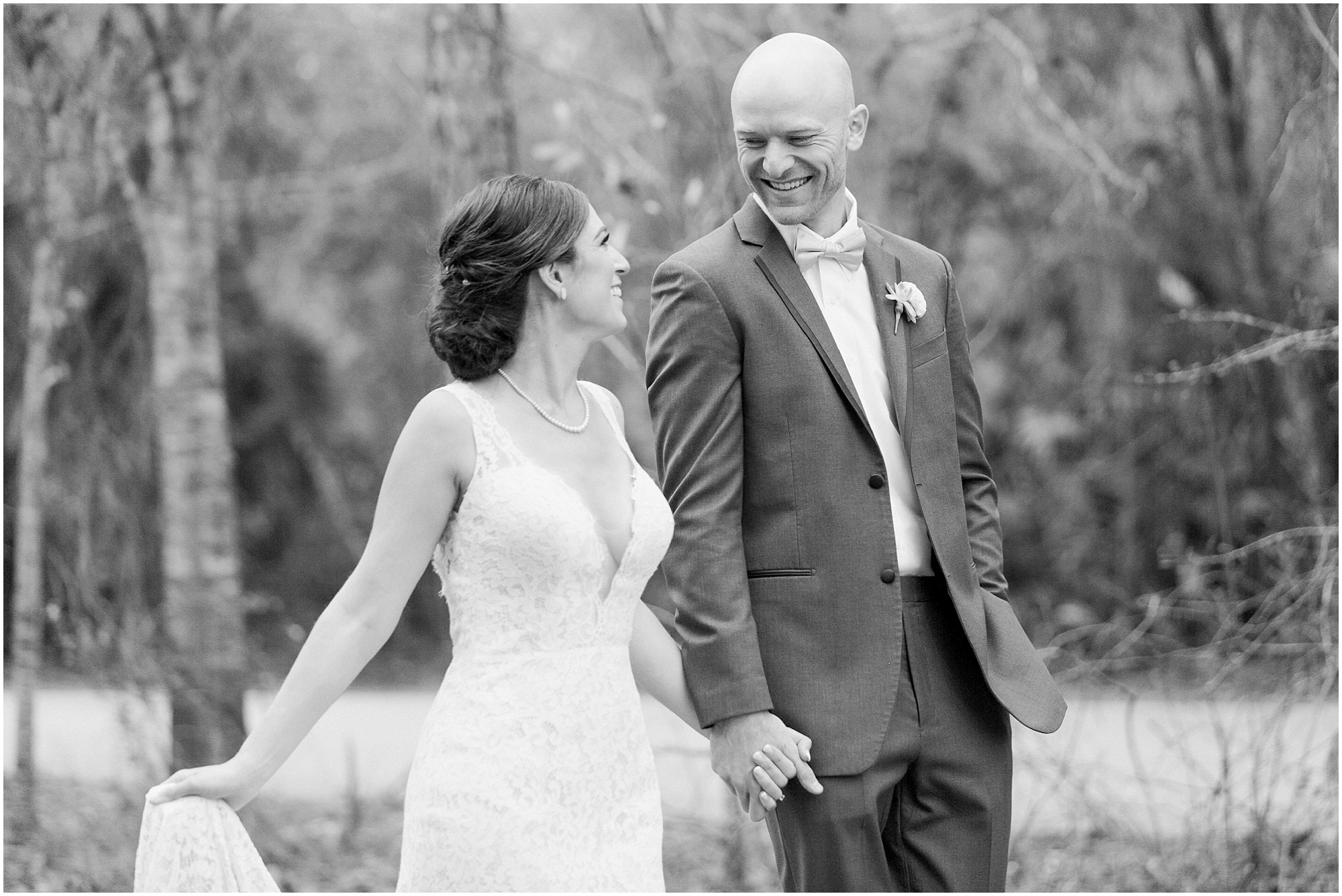 Black and white photo of the bride and groom smiling while walking down the street.