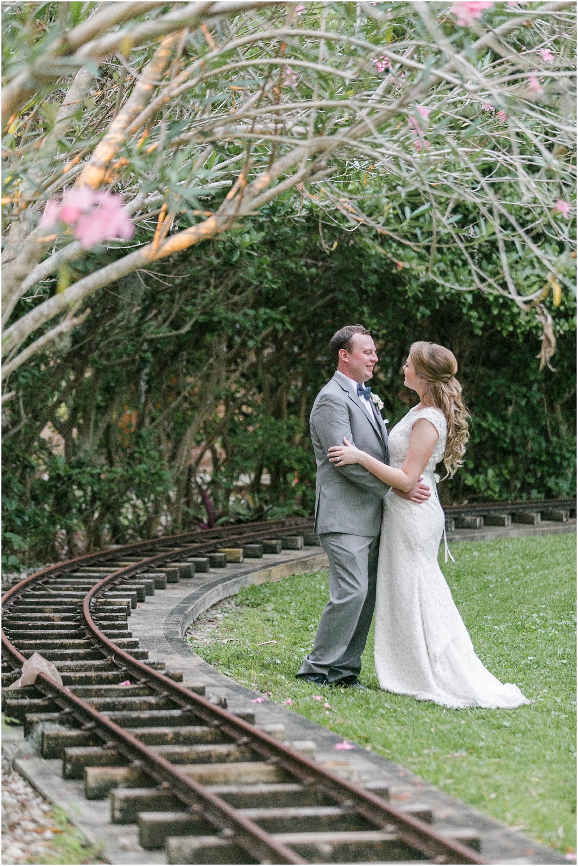 Bride and groom holding each other and looking into each other's eyes while standing next to a railroad.