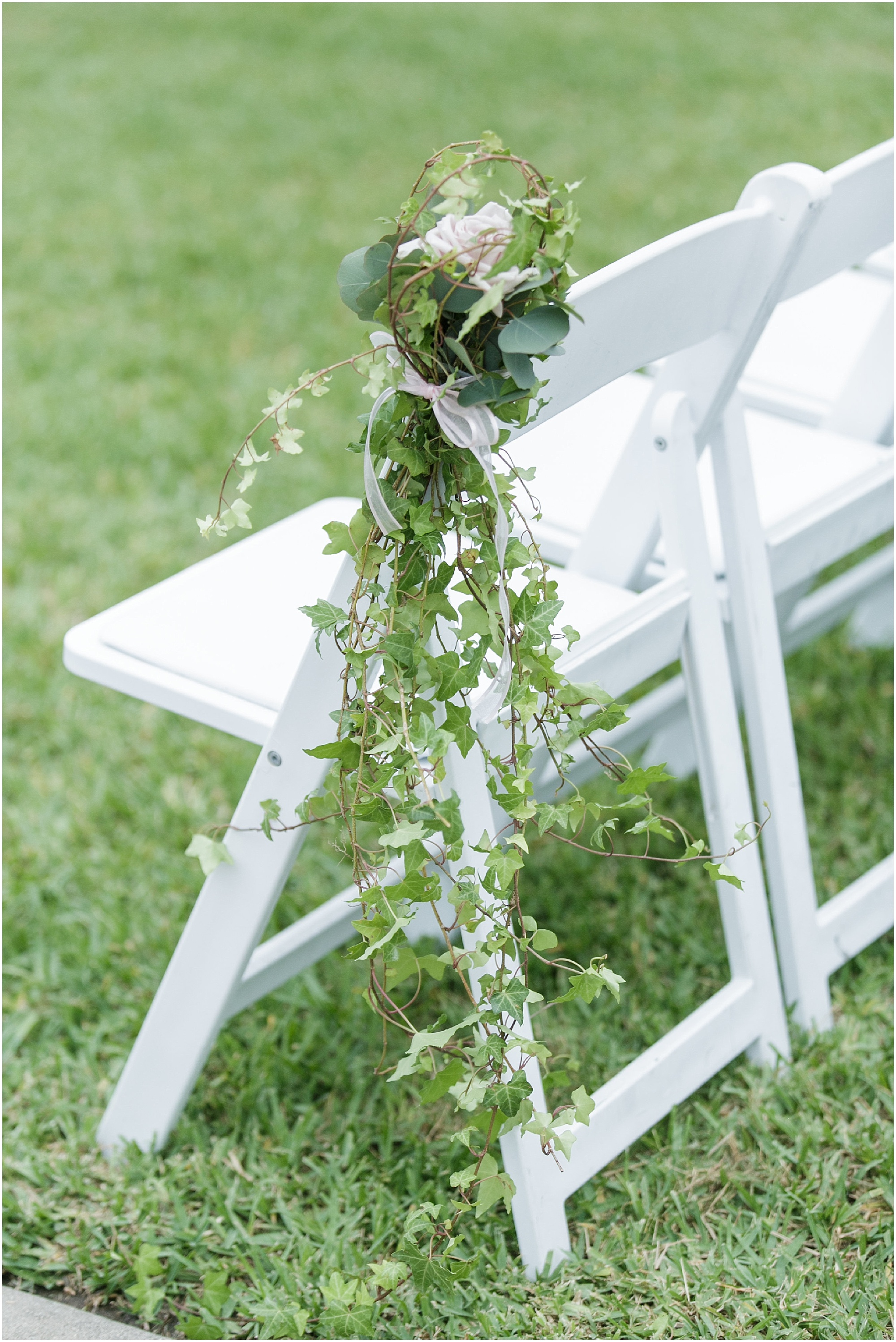 Wedding ceremony chairs with greenery decorating the corner of them. 