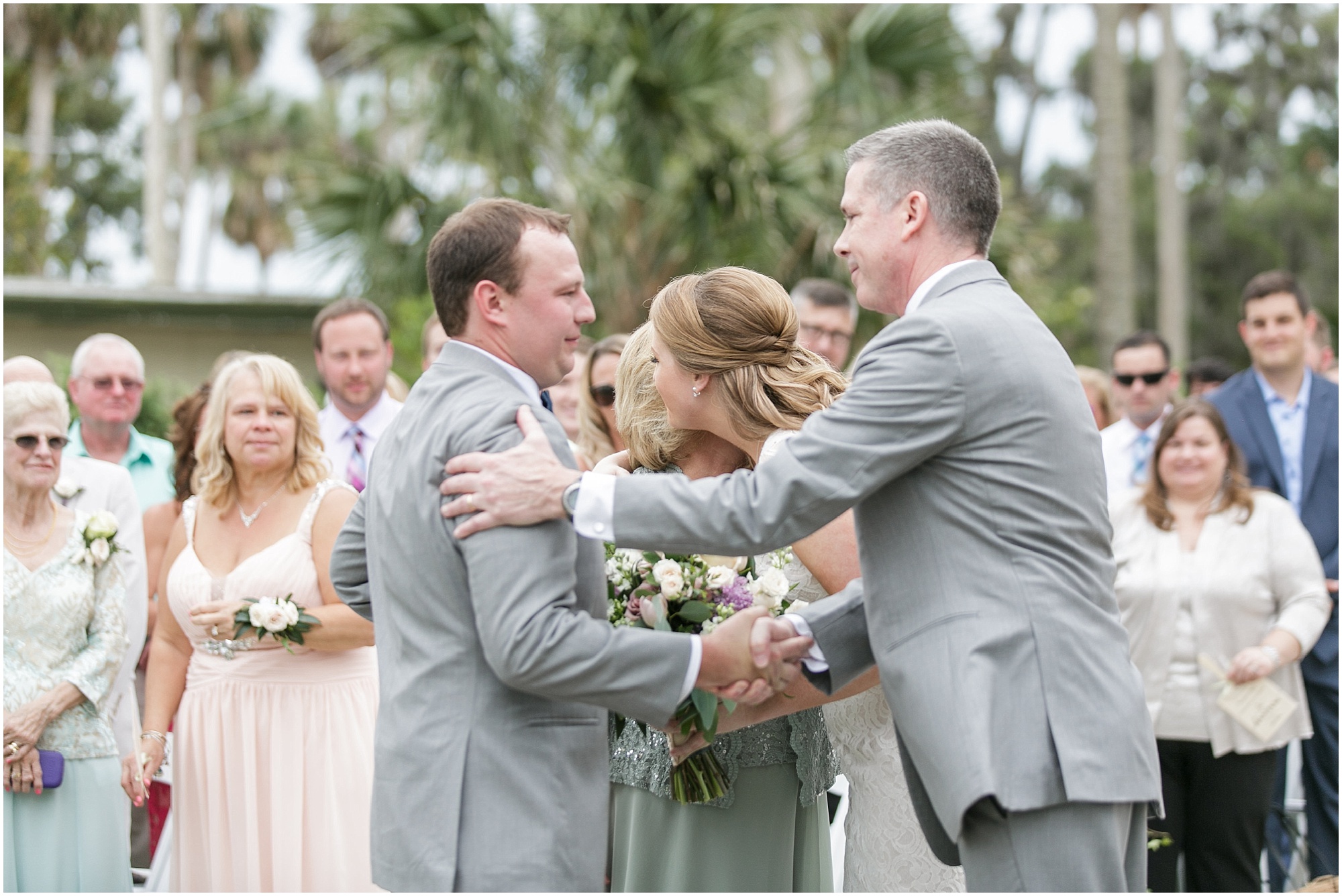 Bride hugs her mom and groom shakes her dad's hand.