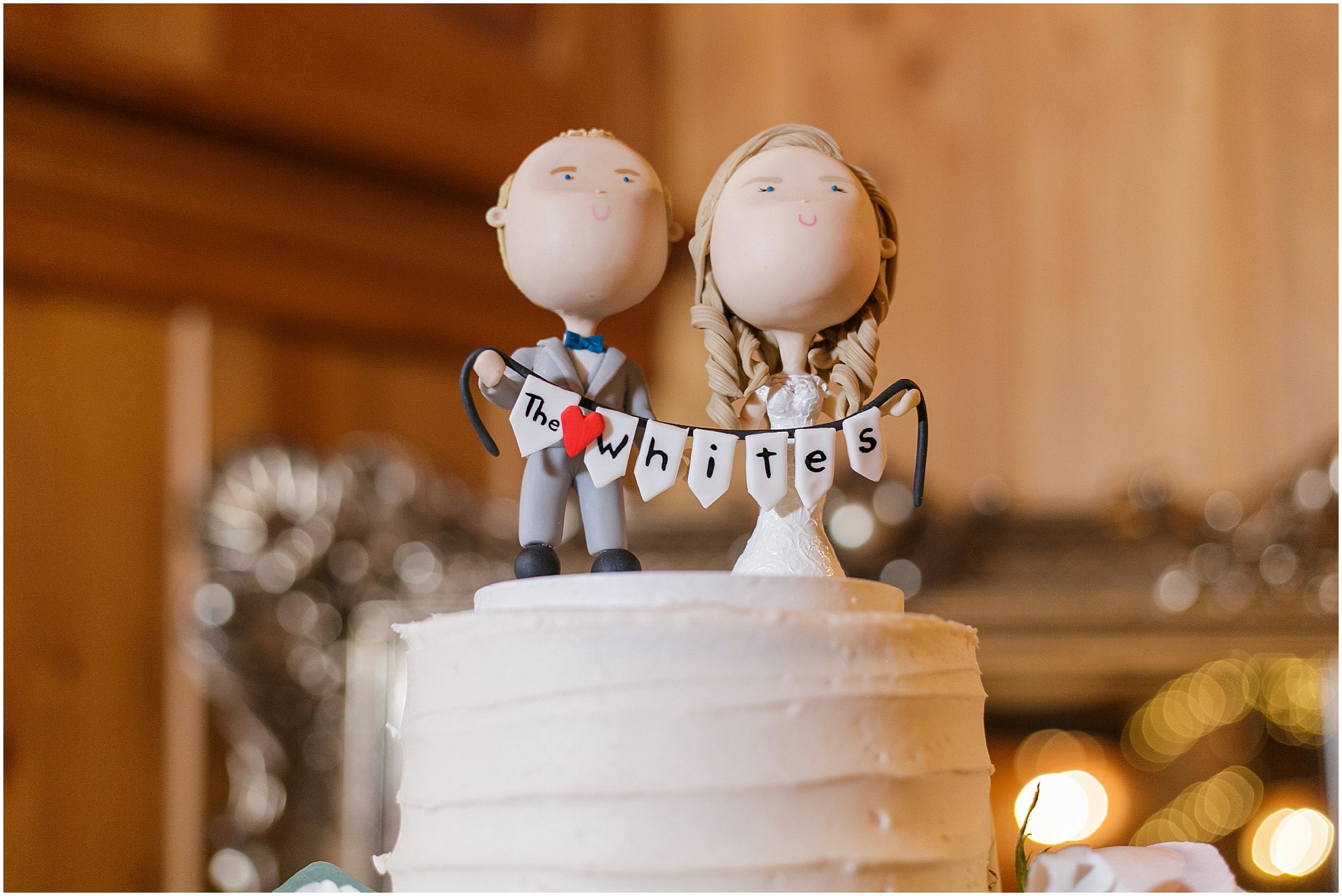 Wedding cake topper of the couple holding a sign with their last name.