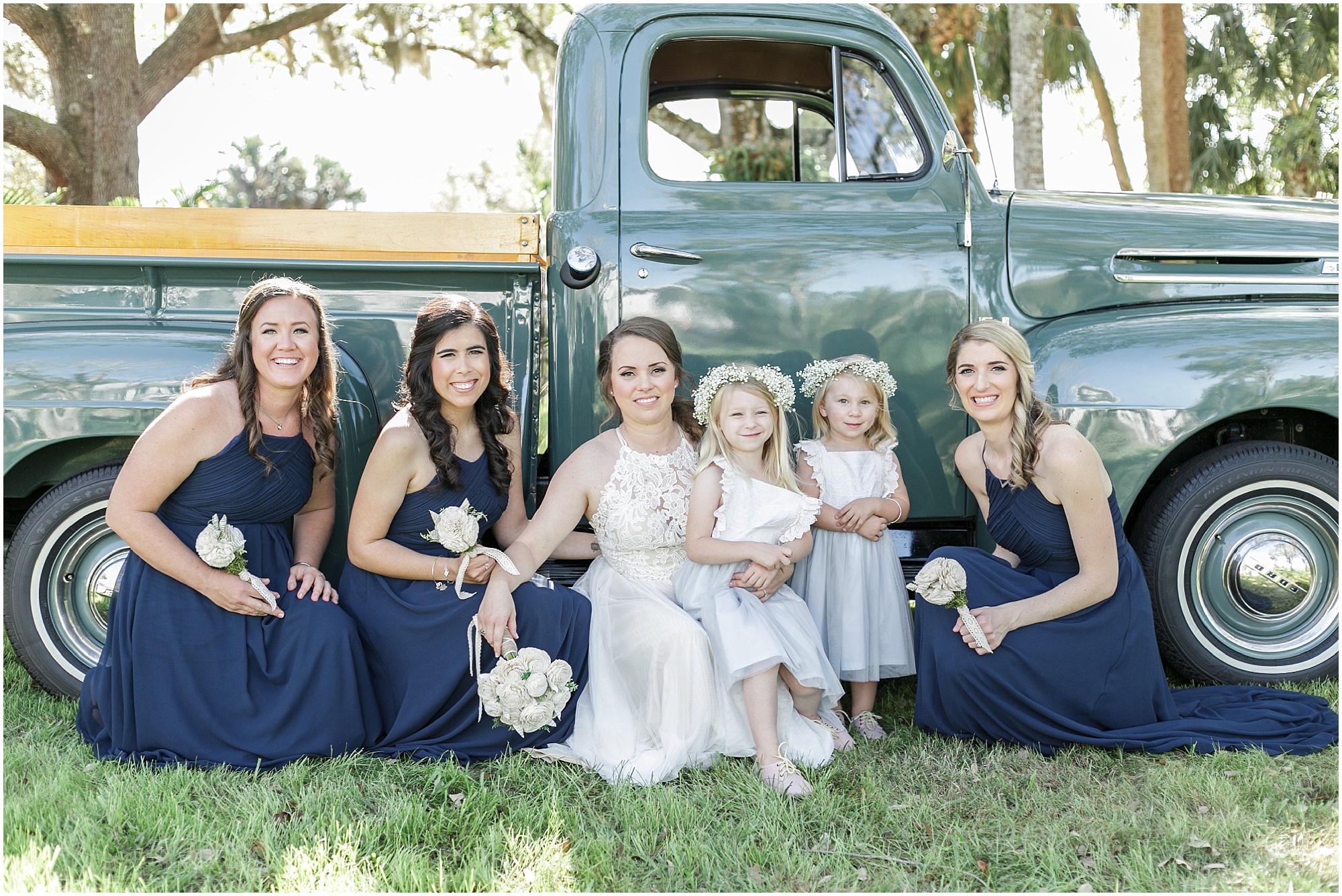 Bride with her bridesmaids and flower girls in front of a green vintage truck