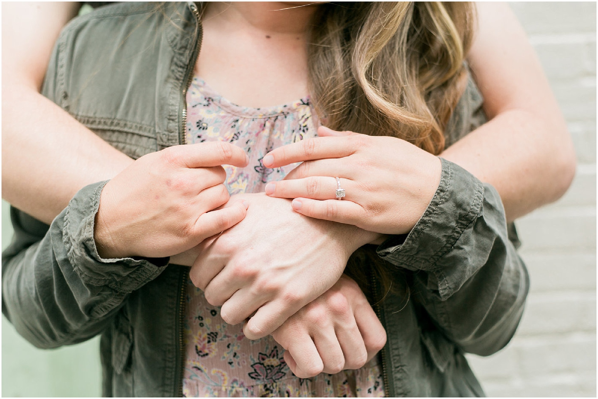 Photo of girl wearing and engagement ring while guy hugs her.