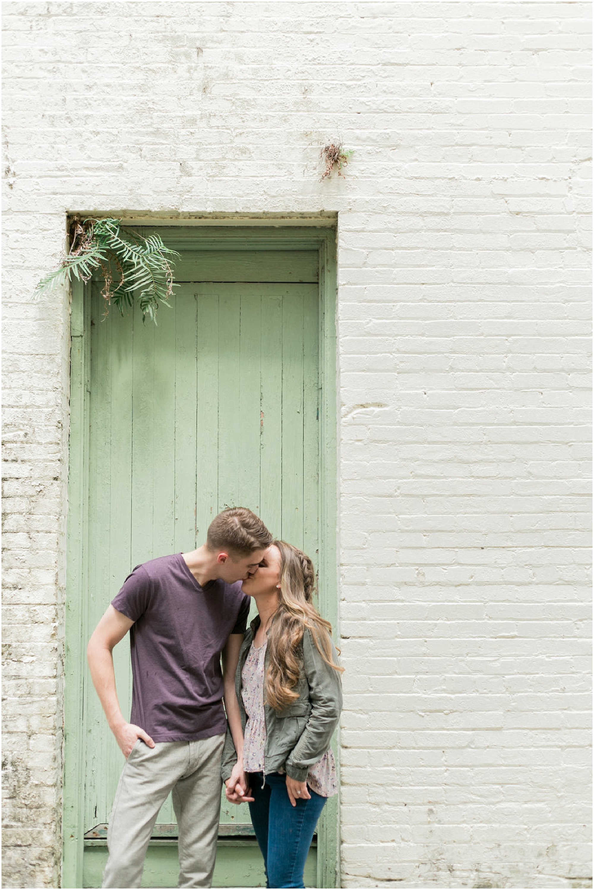 Engaged couple kissing in front of historic green door in Sanford, FL.