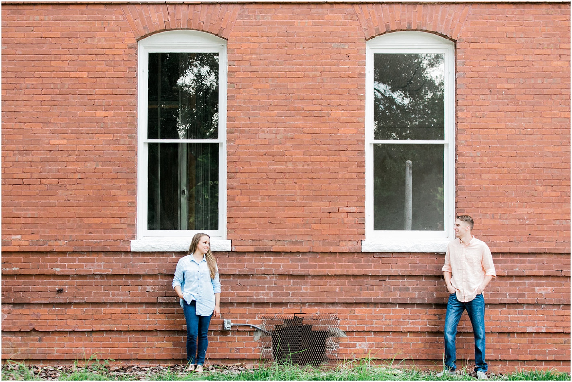 Engaged couple standing on the outside of an old brick building.