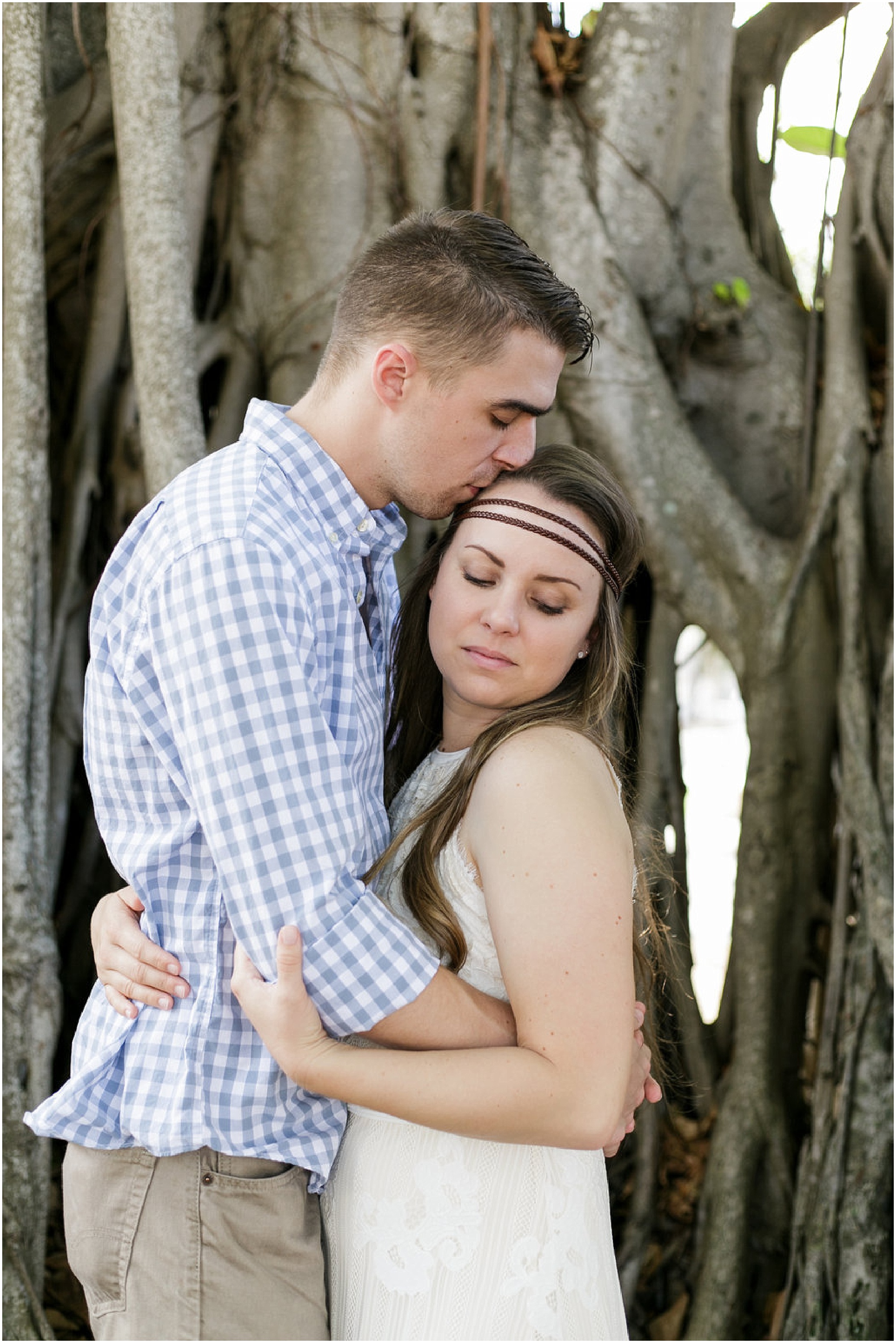 Couple hugging while surrounded by old trees. 