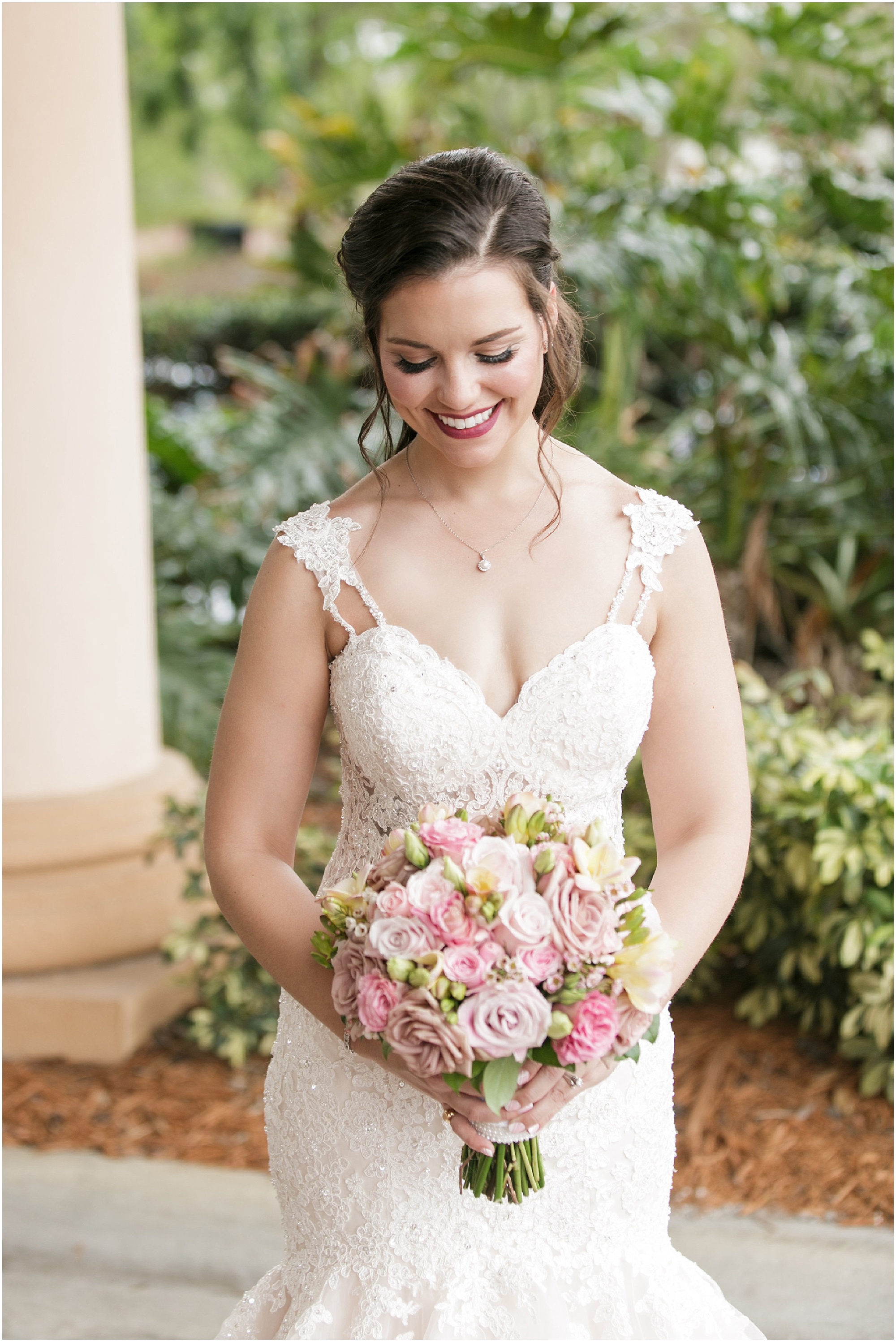 Bride looking down at her pink and blush flower bouquet. 