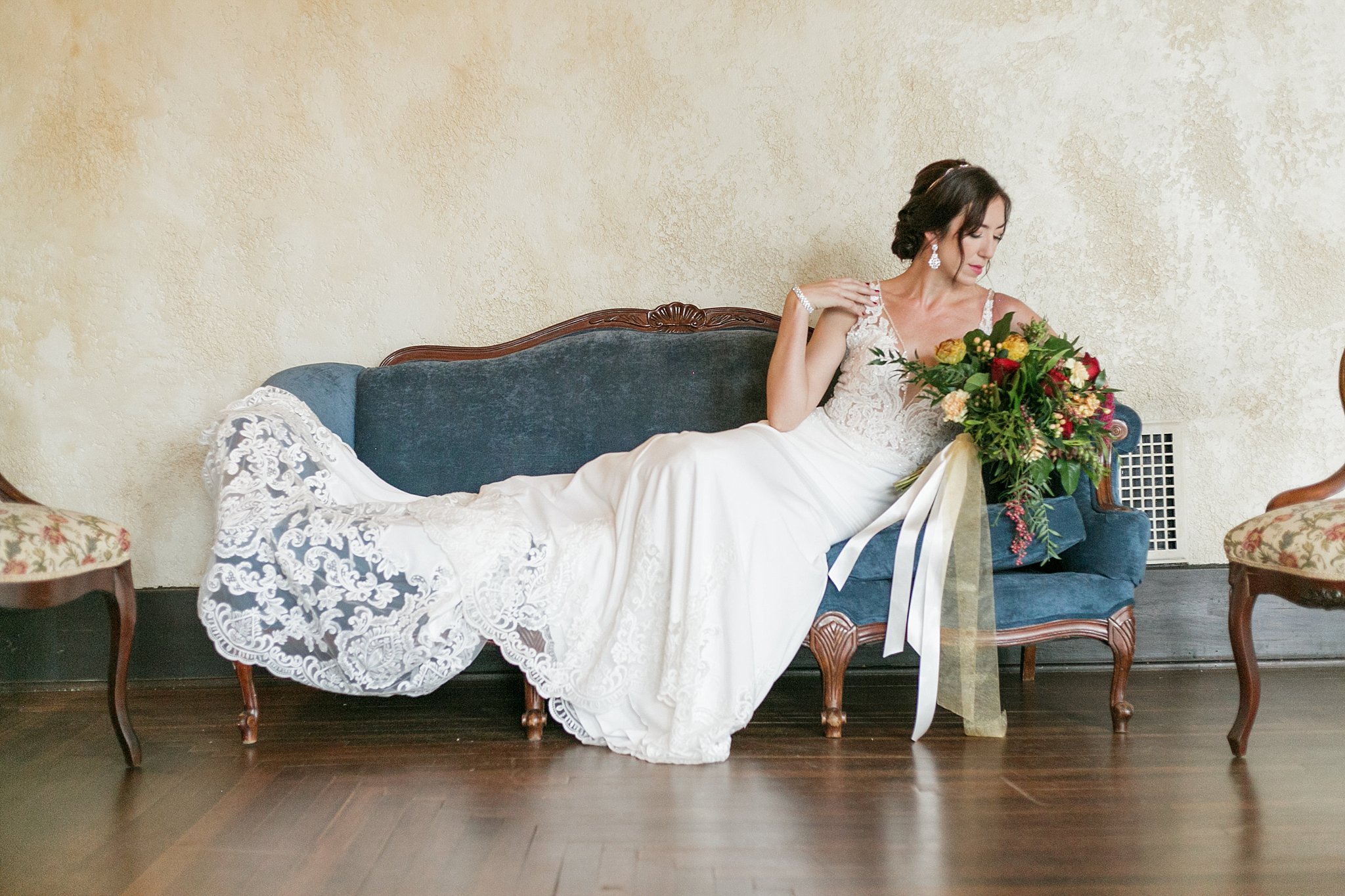 Full shot of the bride lounging on an antique blue couch.