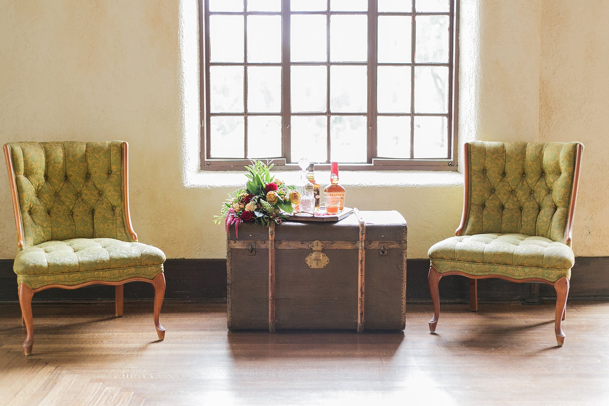 Antique olive chairs flanking an old steamer trunk.