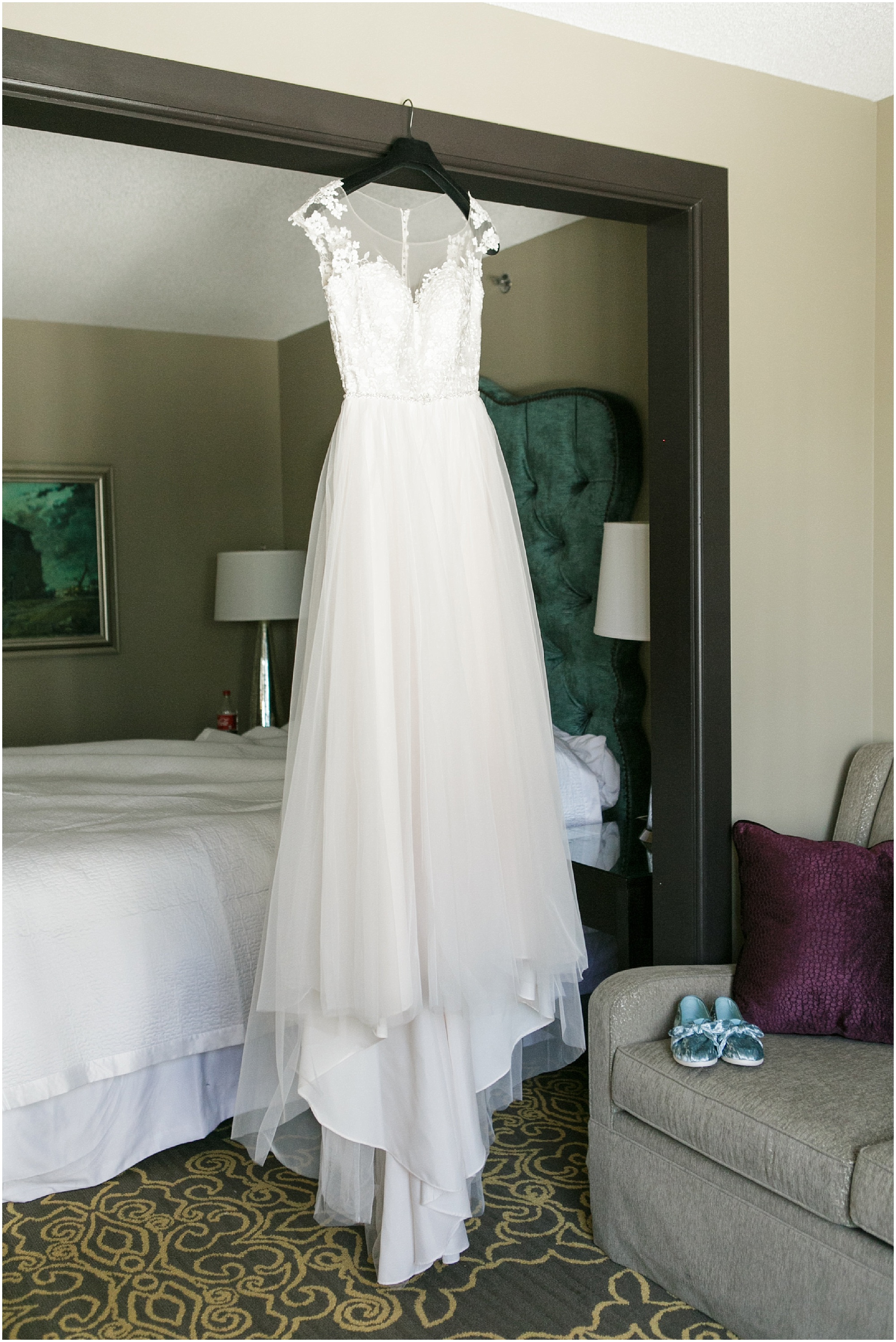 Bride's wedding dress hanging from a doorframe. 