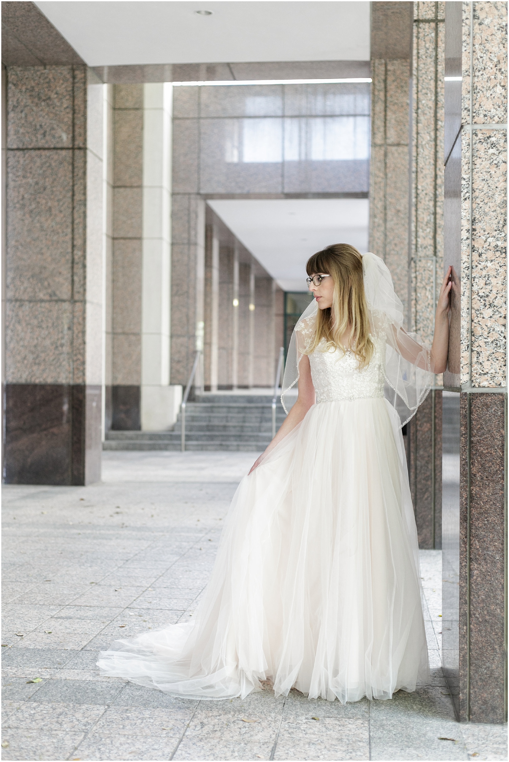 Bride posing in a breezeway in her wedding dress.