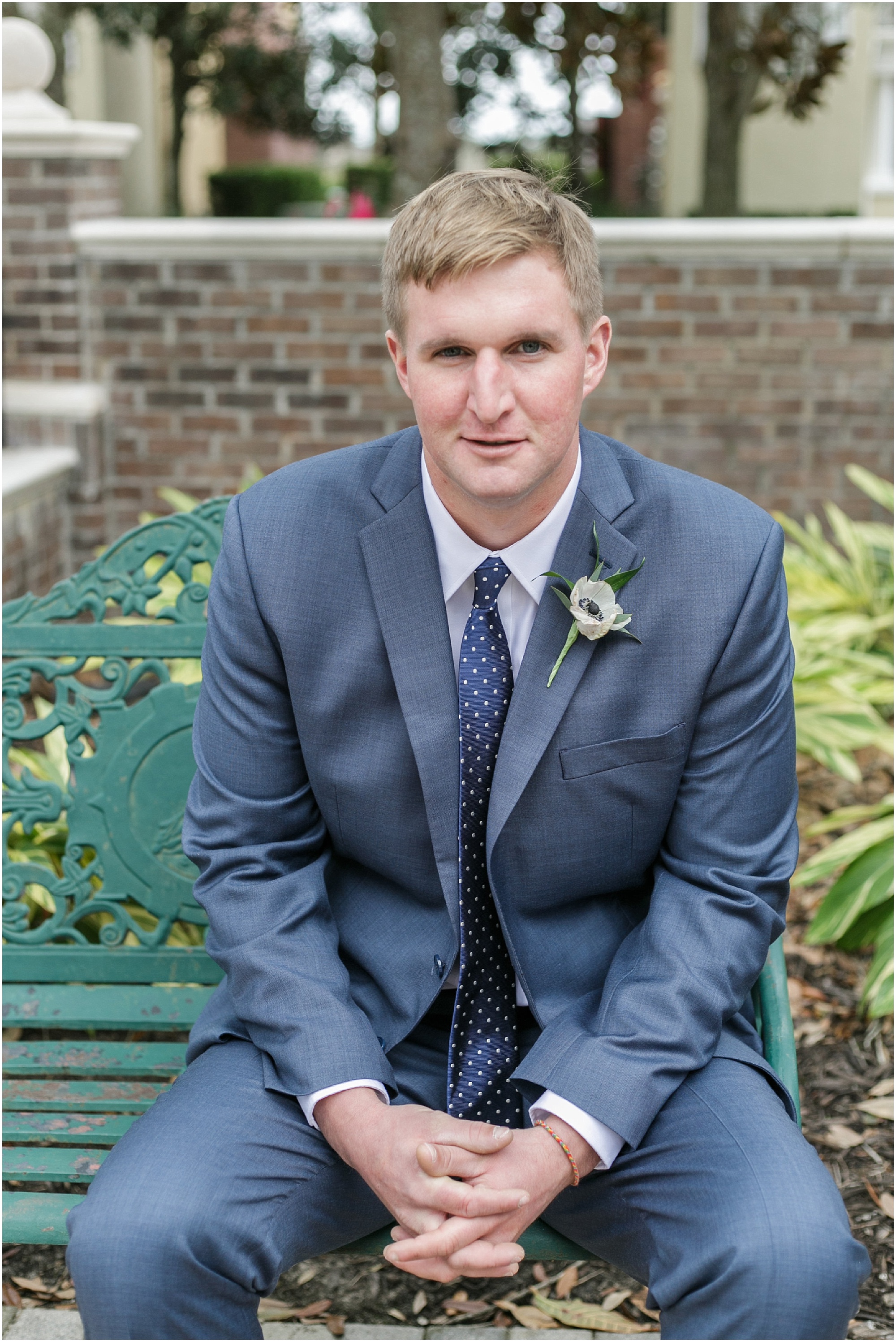 Portrait of the groom in a blue suit sitting on a bench. 