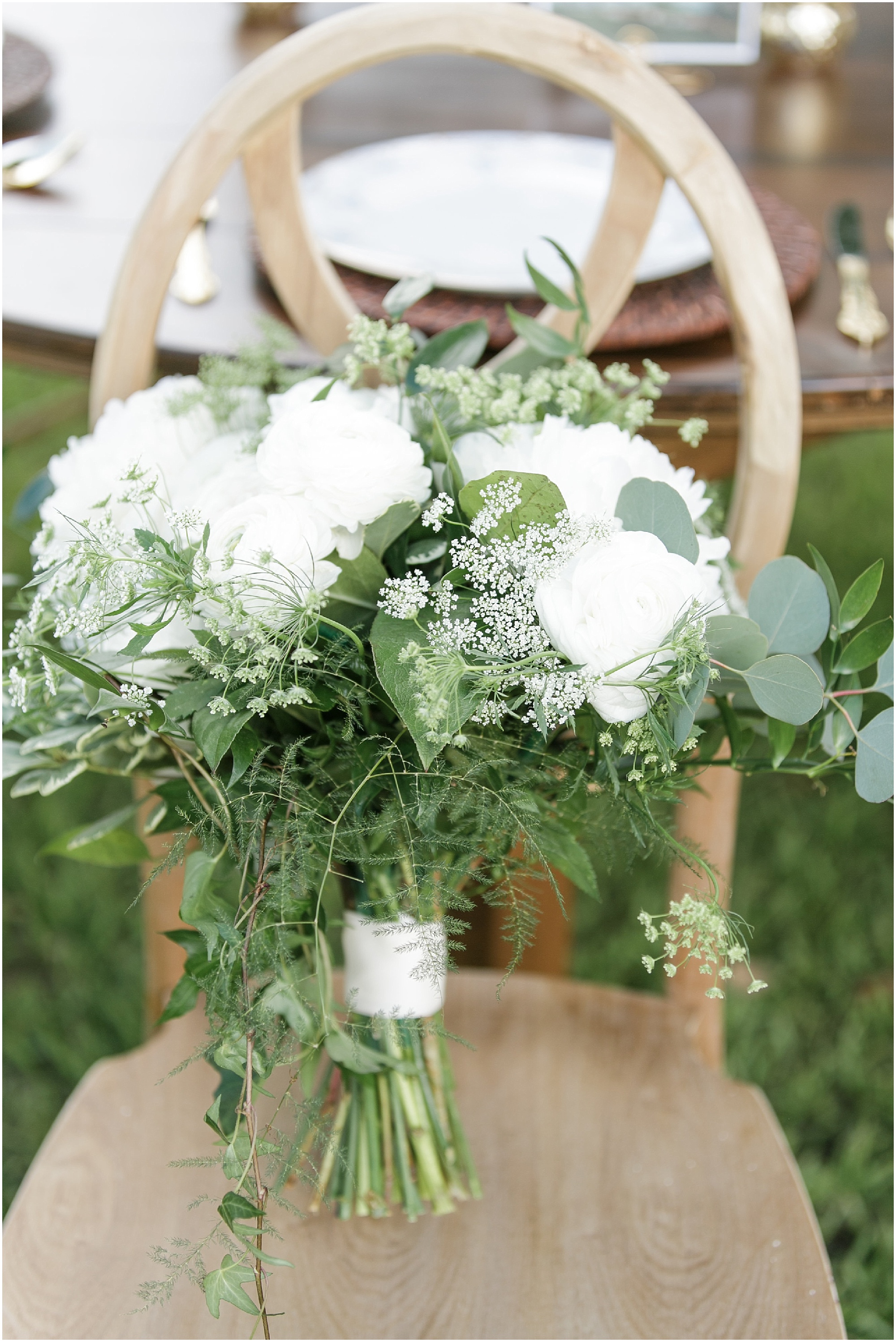 Green and white bouquet sitting in a wooden chair. 