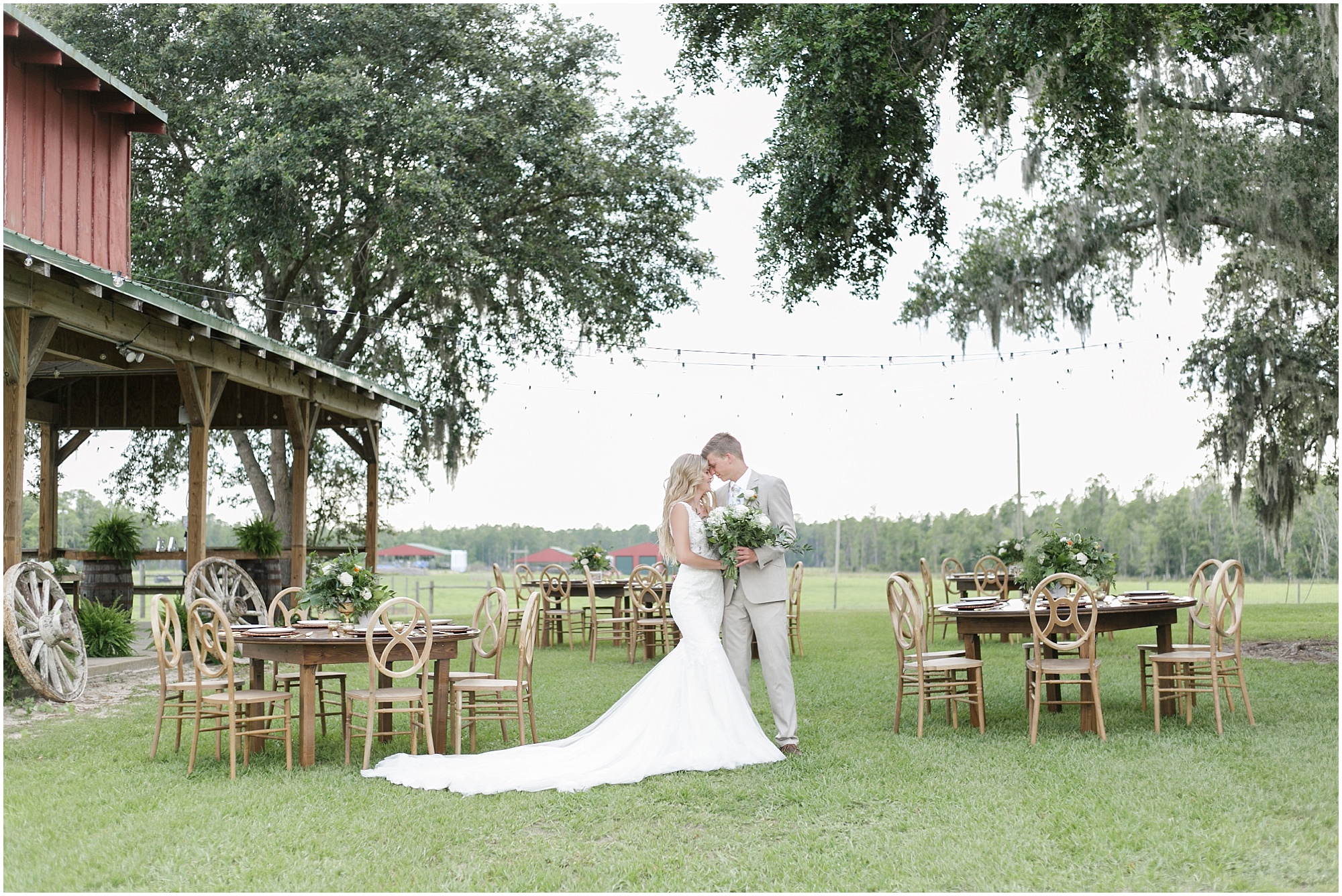Wide shot of the bride and groom standing in their outdoor wedding reception. 