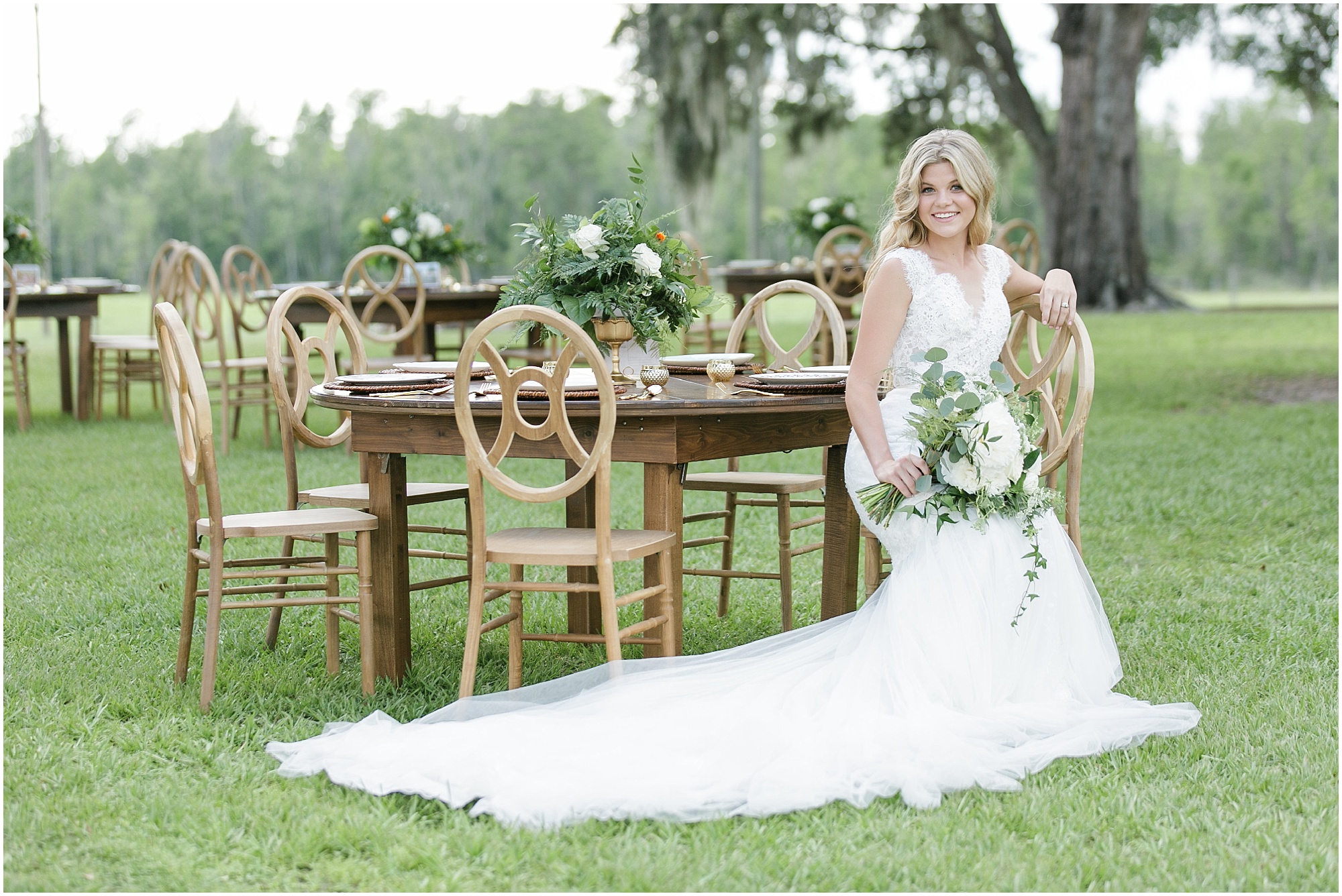 Bride sitting at a reception table holding her large green and white bouquet.