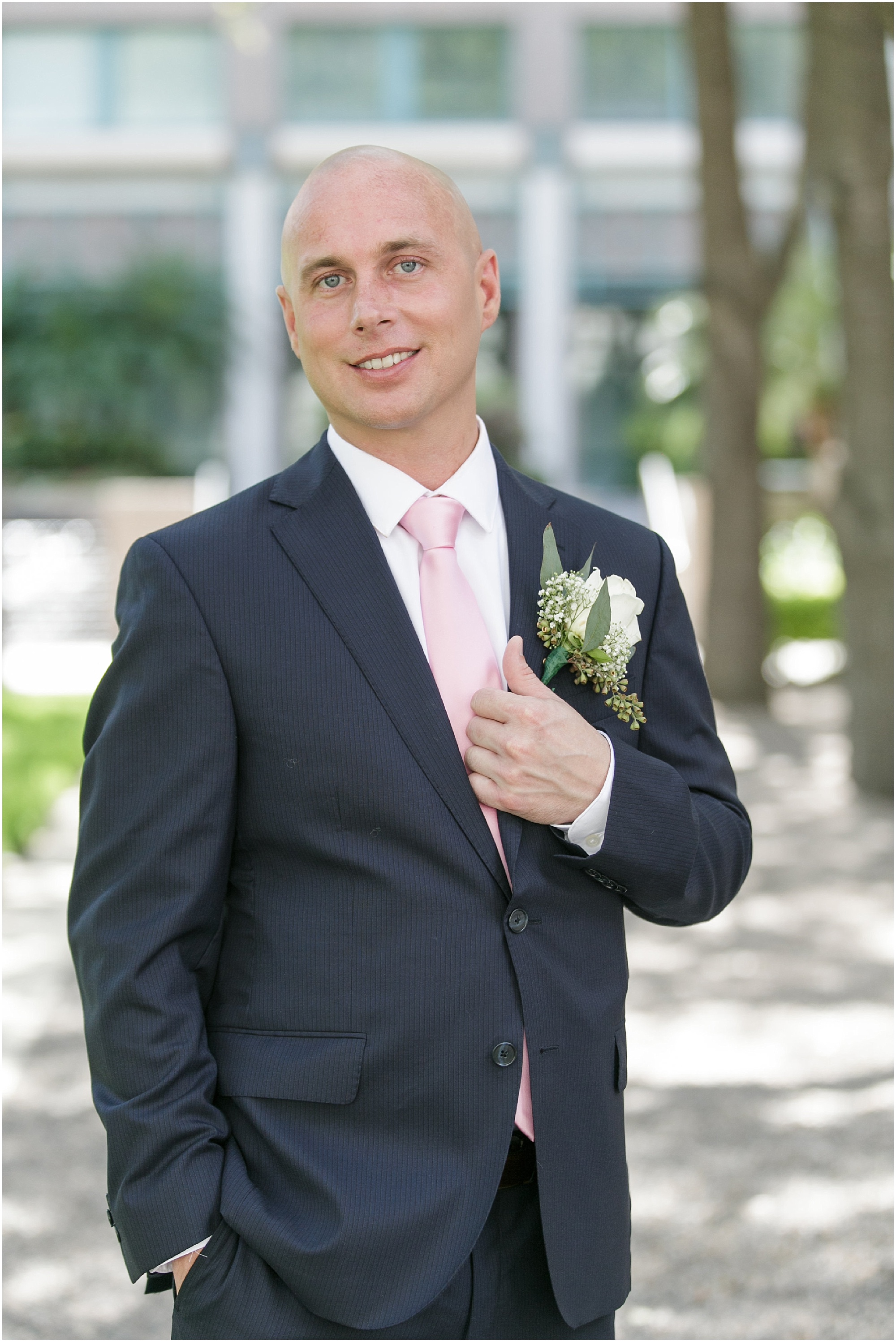 Portrait of the groom in her dark blue suit and soft pink tie. 
