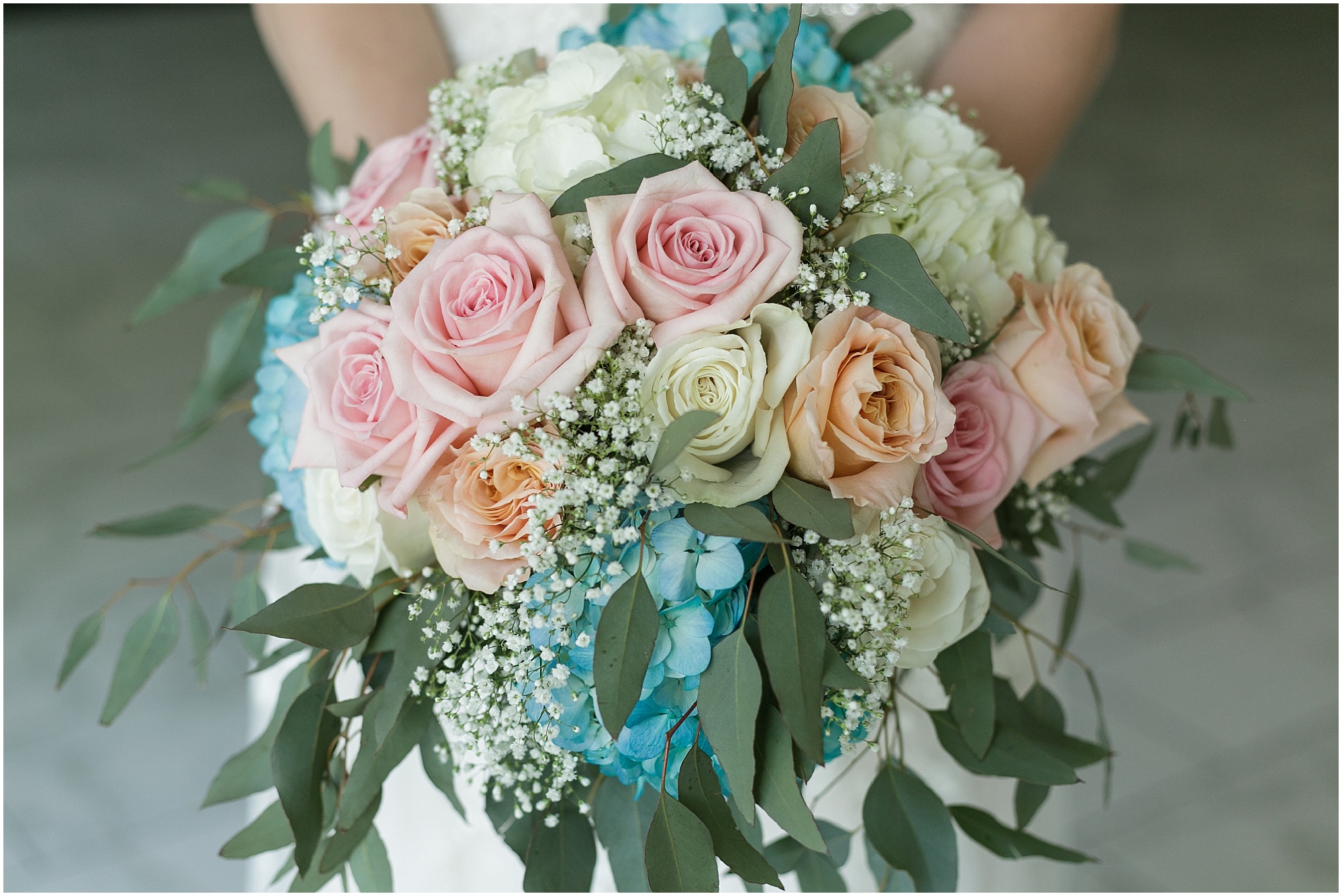Close photo of the brides colorful bouquet in shades of light pinks, blues, and peach. 
