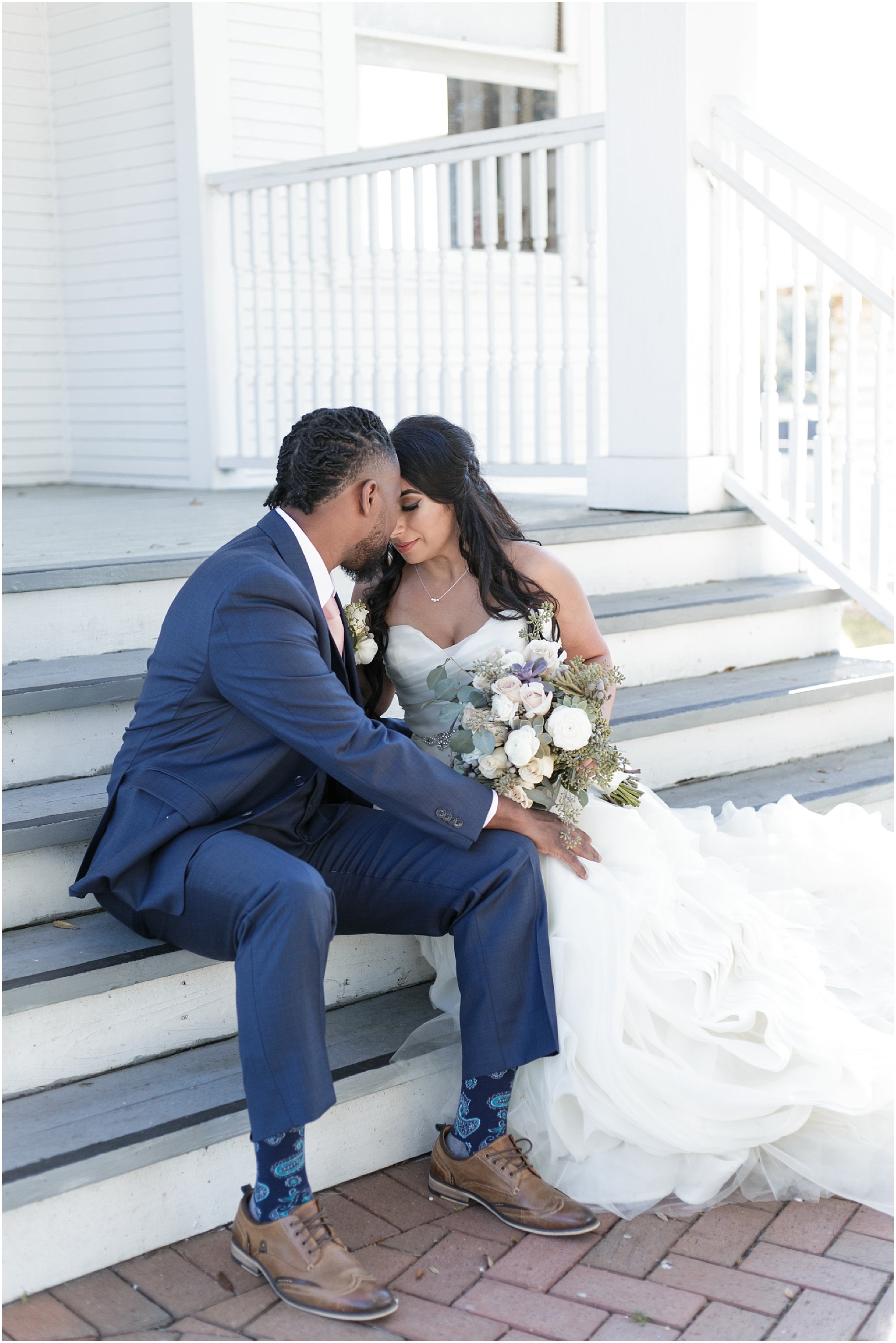 Bride and groom snuggling while sitting on steps of a library.