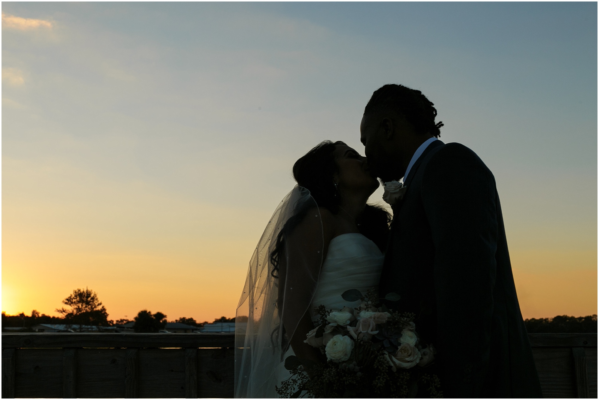 Silhouette of the bride and groom kissing in the sunset. 