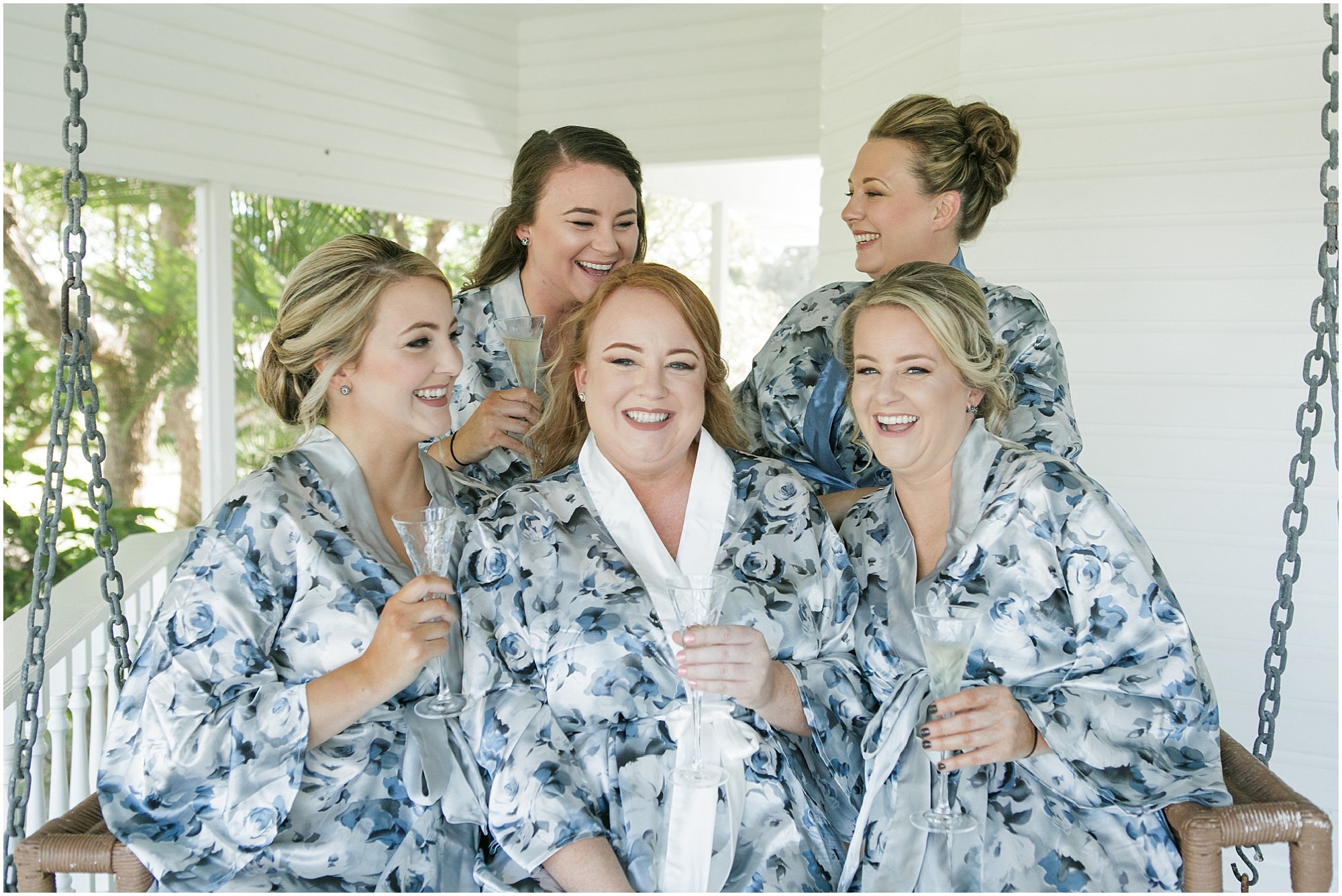 Bride and her bridesmaids sitting on a swing in their robes before getting ready. 