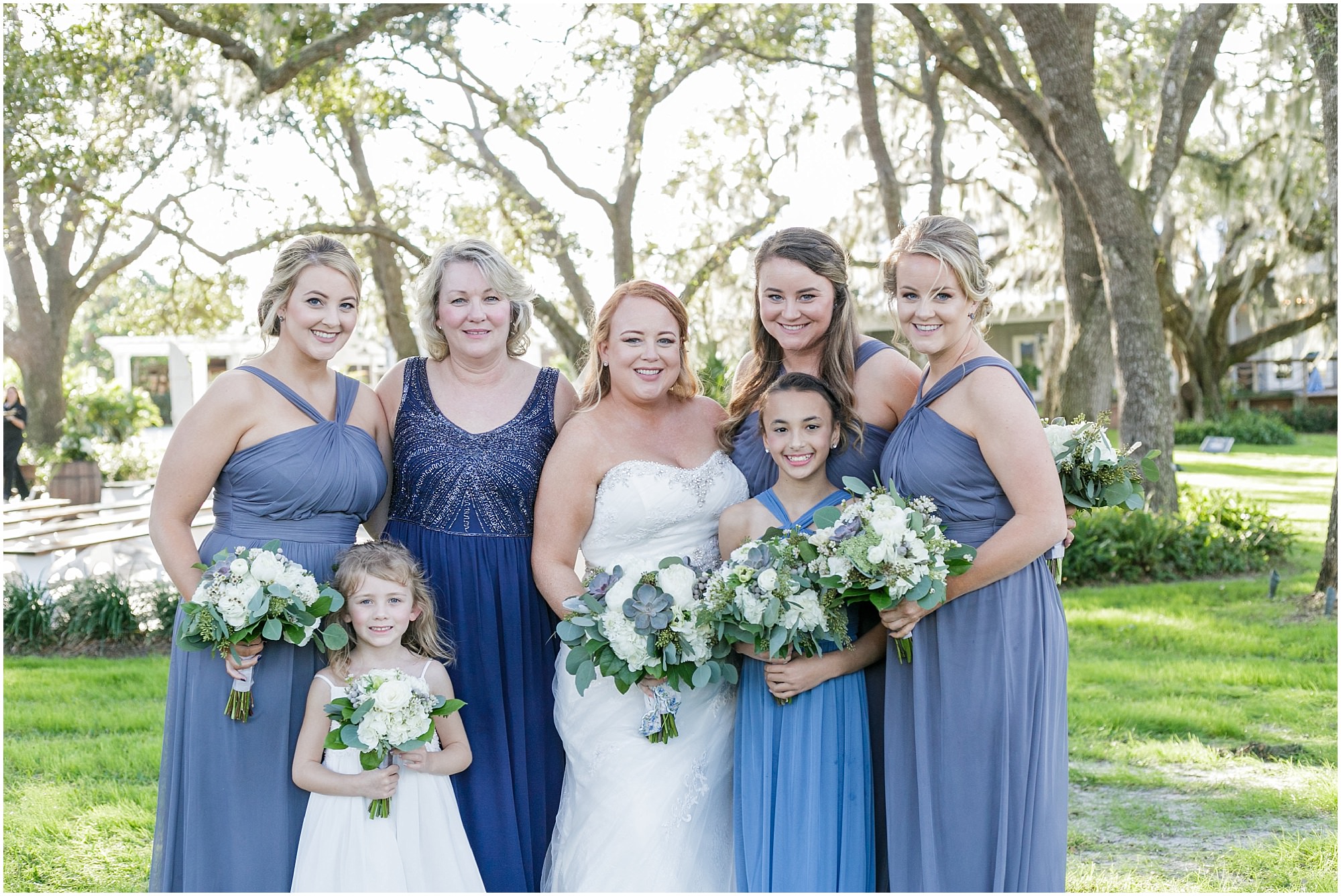 Bride and her bridal party pose for photos outdoors. 